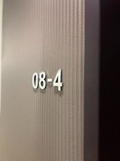 Nahaufnahme einer Tür mit der Nummer 08-4 auf einer strukturierten Oberfläche.