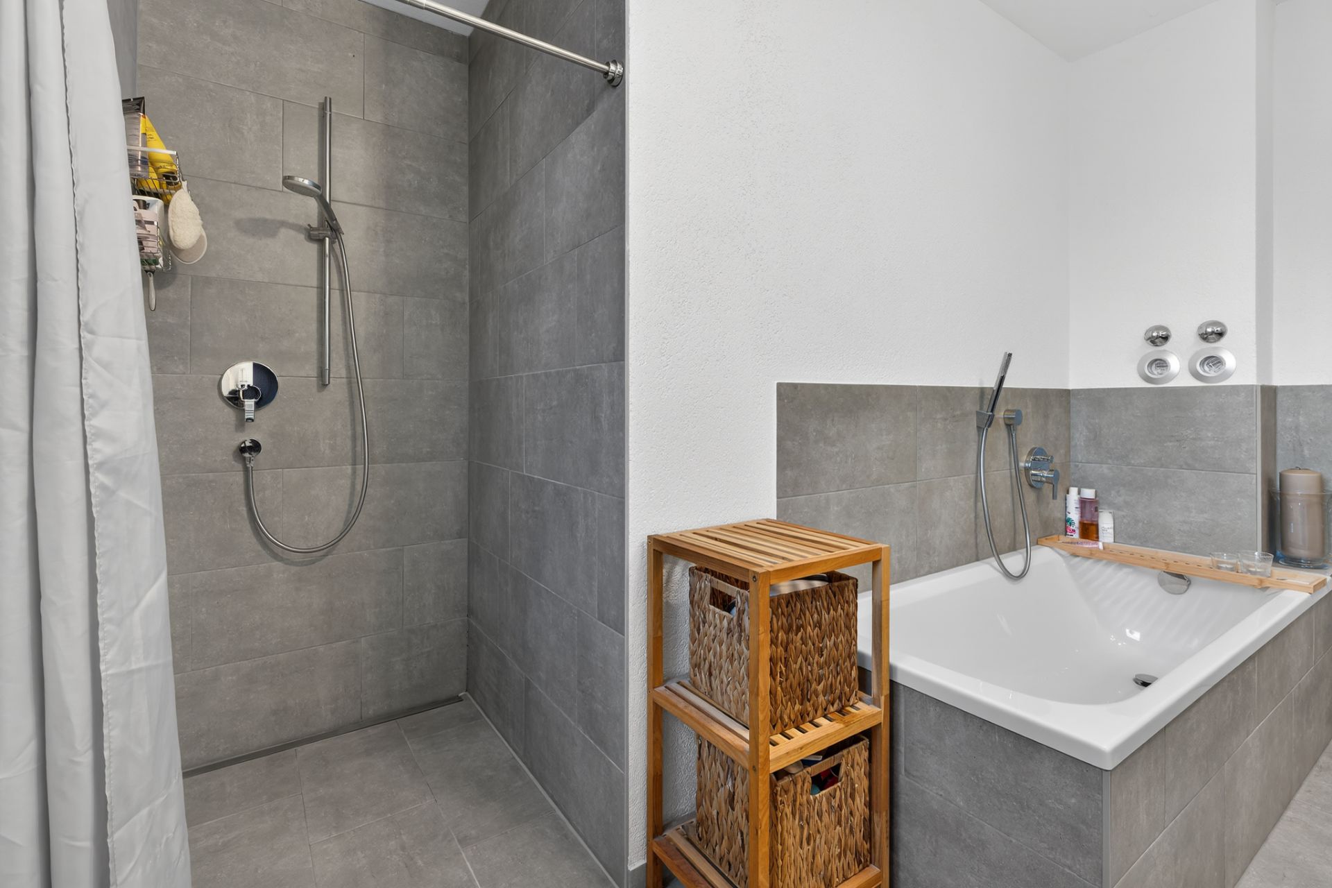 Modernes Badezimmer mit bodengleicher Dusche, Badewanne und Holzregal mit Körben.