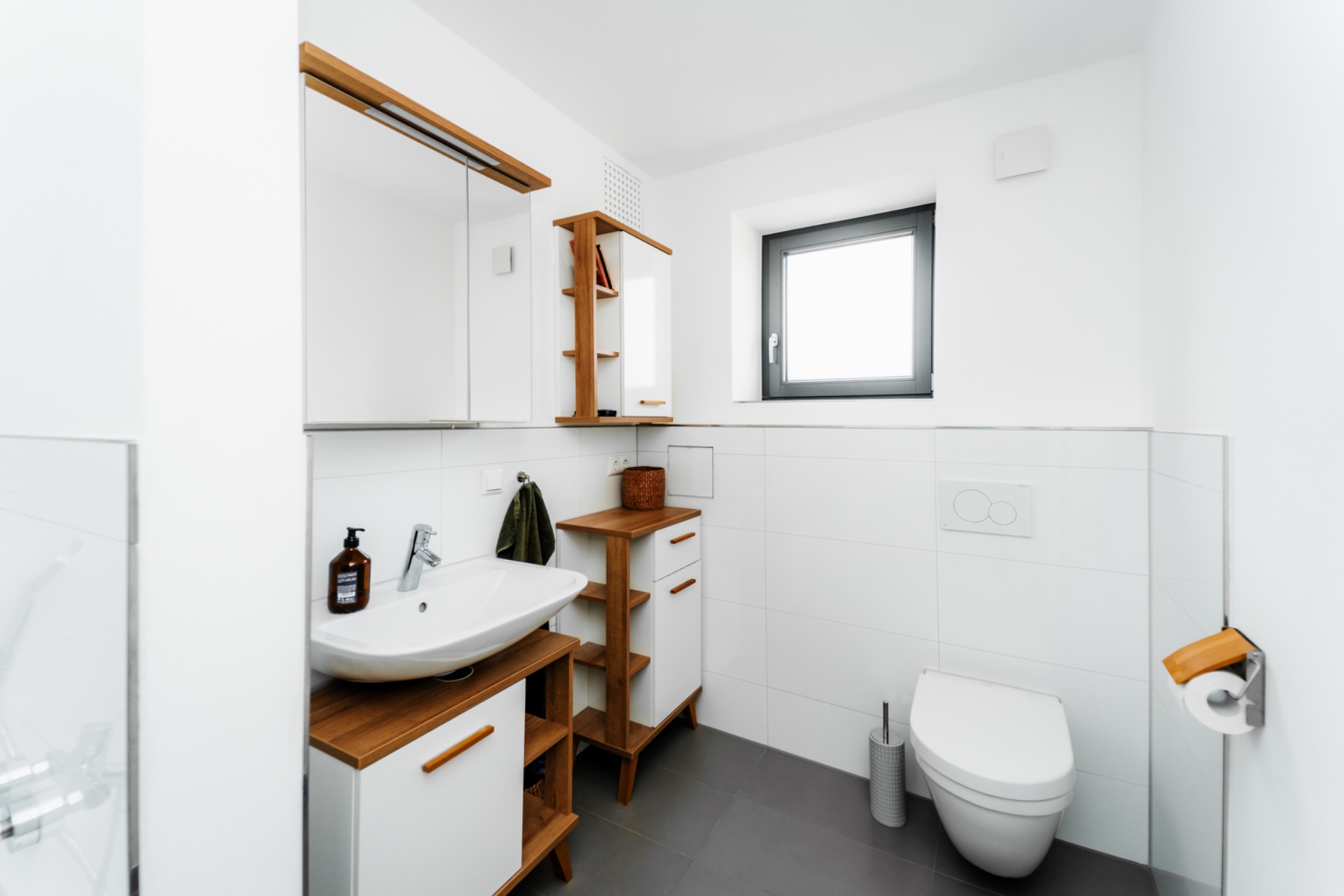 Modernes Badezimmer mit Waschbecken, Spiegel, Toilette und Fenster.