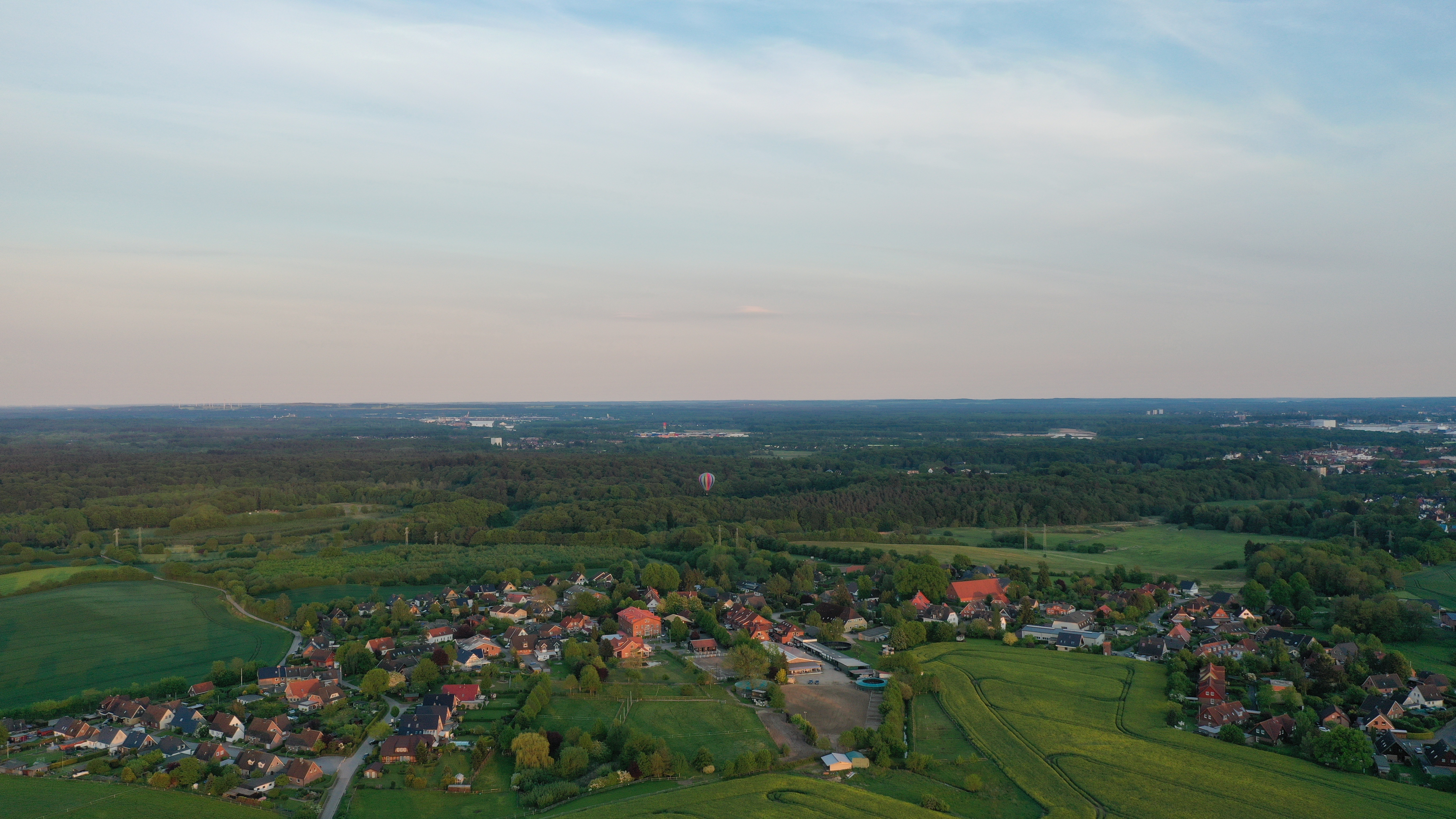 Luftaufnahme eines kleinen Dorfs mit vielen Häusern und grüner Umgebung.
