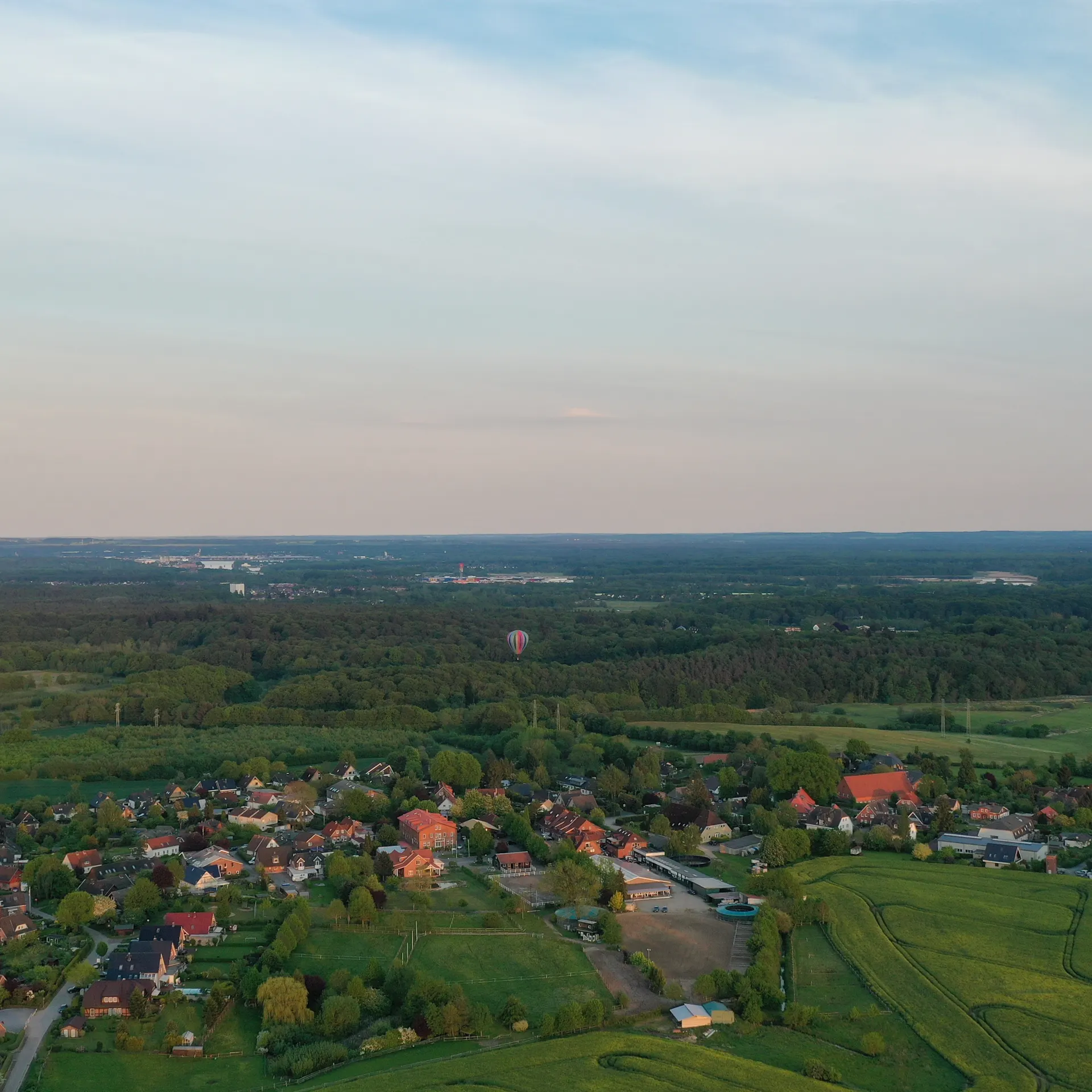 Luftaufnahme eines kleinen Dorfs mit vielen Häusern und grüner Umgebung.