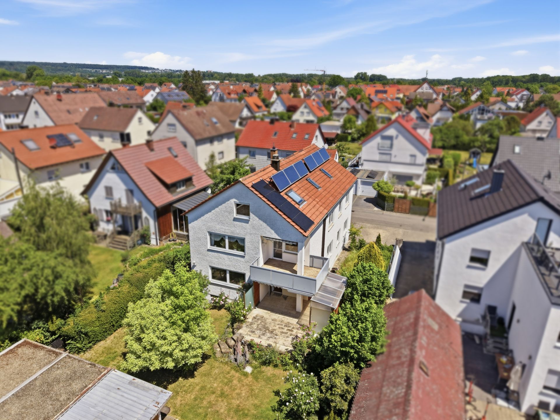 Luftaufnahme eines freistehenden Wohnhauses mit Garten und Solarpaneelen auf dem Dach.