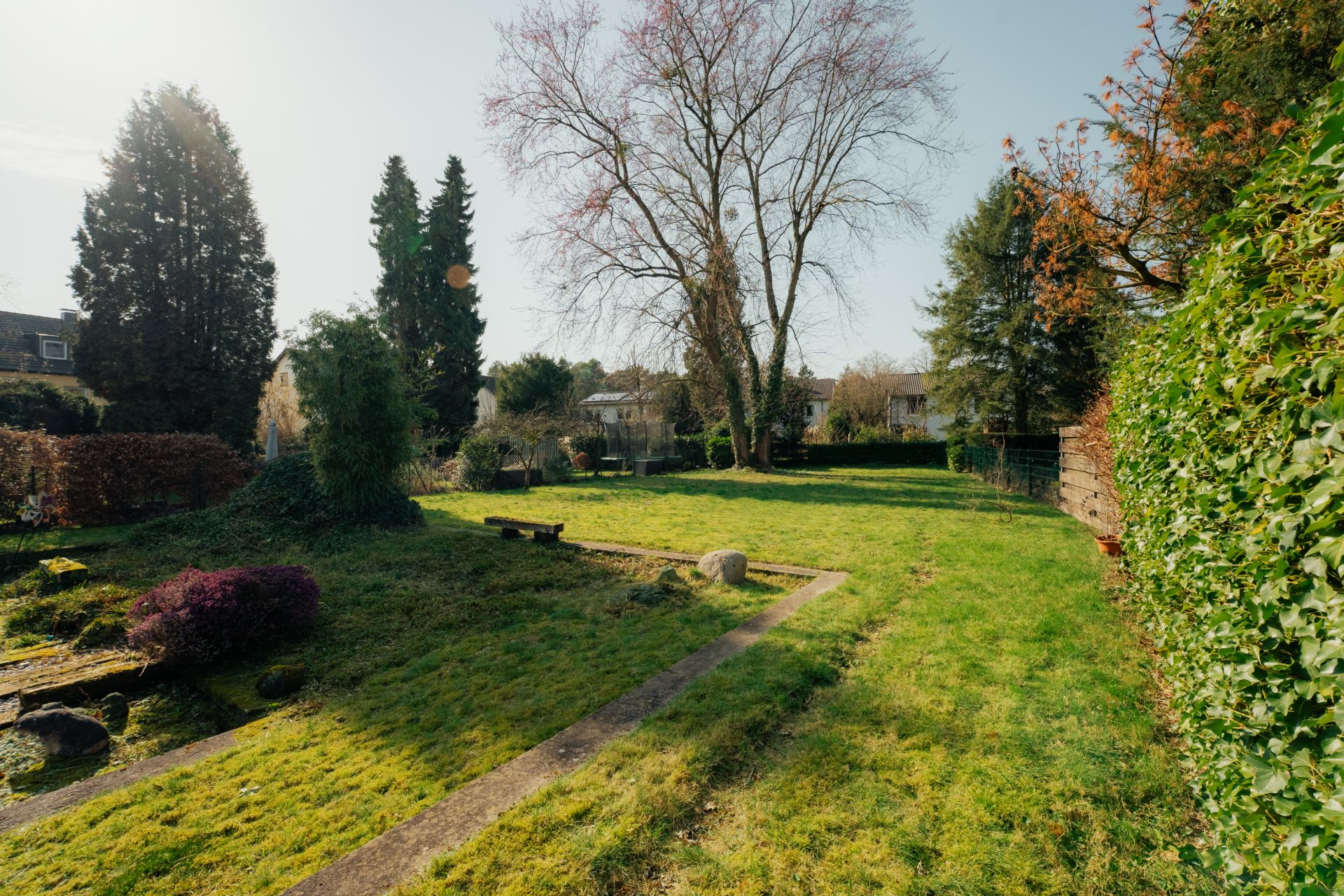 Großer Garten mit Rasenfläche, Bäumen, Büschen und einem schmalen Weg.