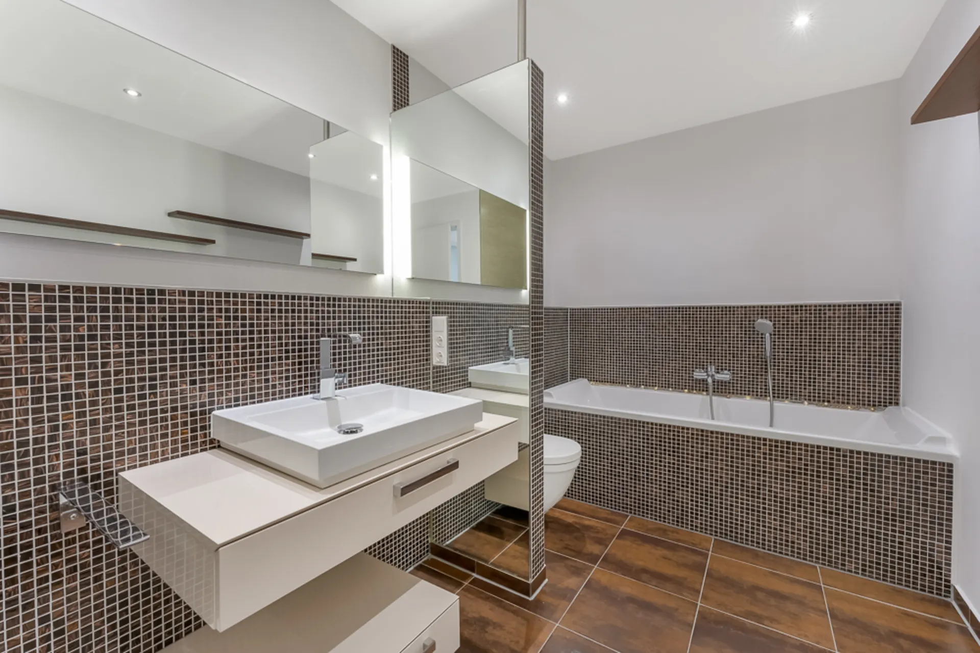 Modernes Badezimmer mit rechteckigem Waschbecken, Badewanne und braunen Fliesen.