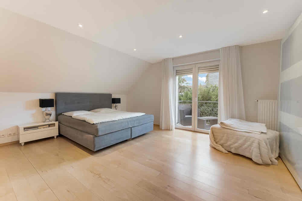 Geräumiges Schlafzimmer mit großem Bett, Nachttischen und Zugang zum Balkon.