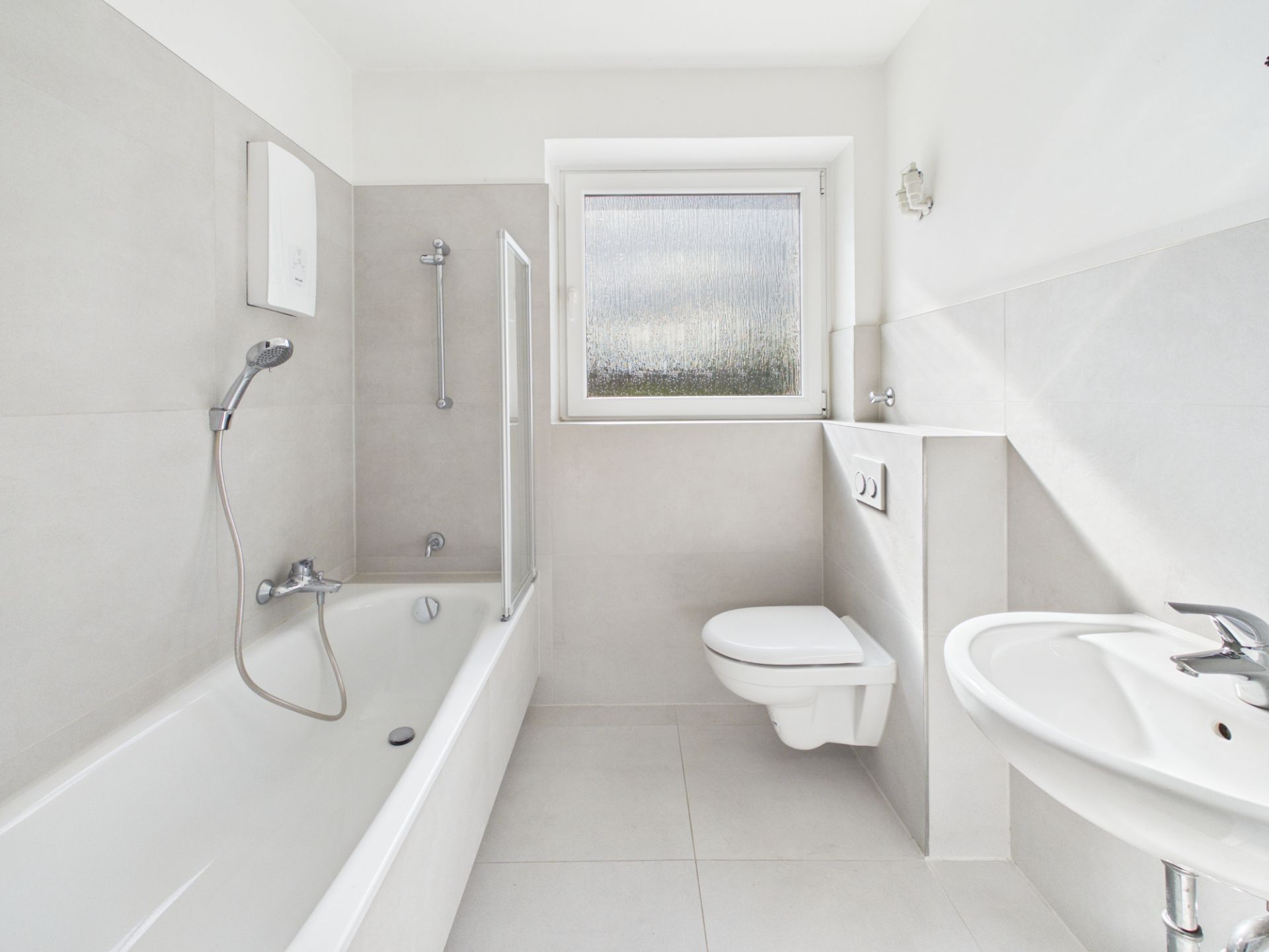 Modernes Badezimmer mit Badewanne, WC, Waschbecken und Fenster.