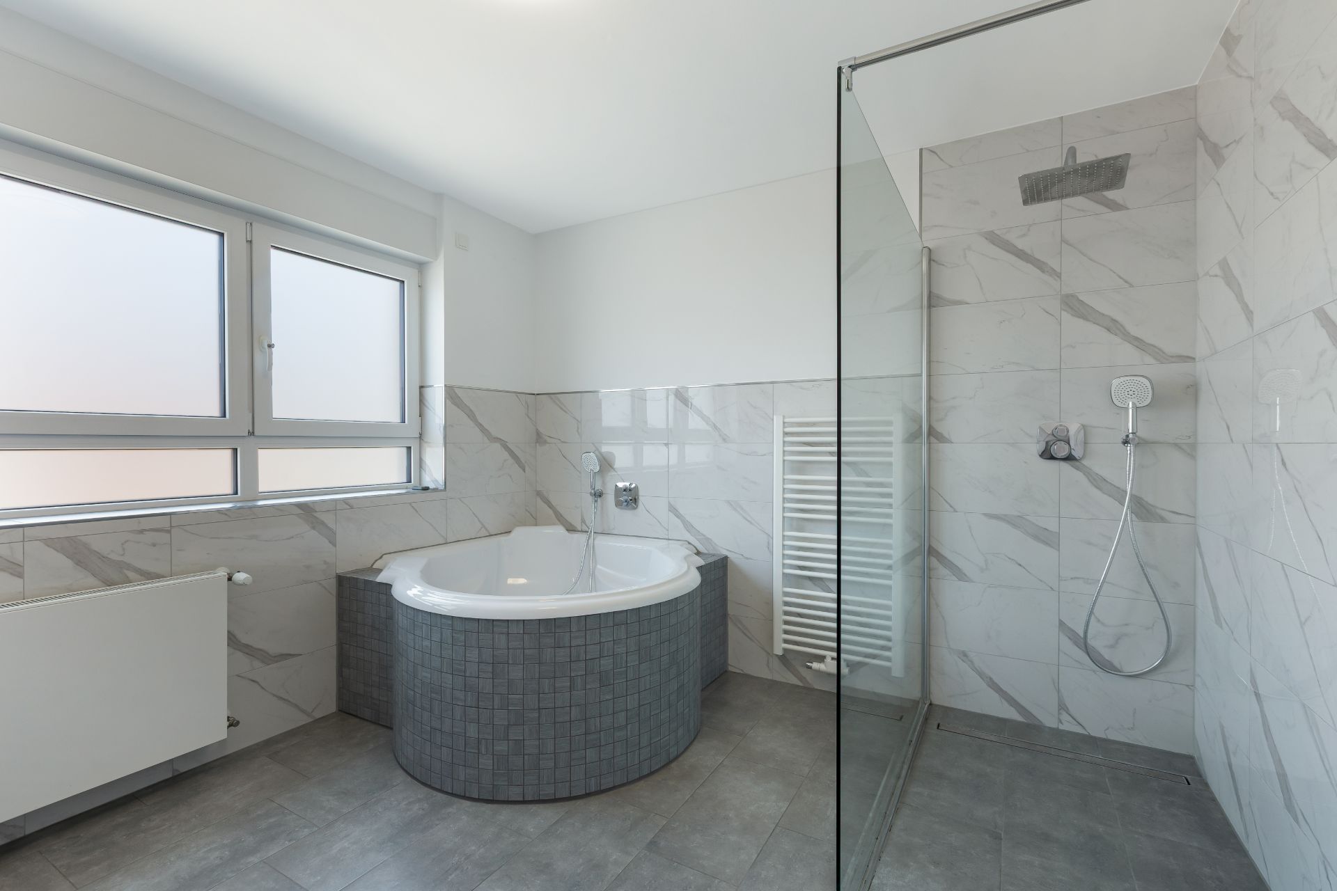 Modernes Badezimmer mit Eckbadewanne, bodengleicher Dusche und großem Fenster.