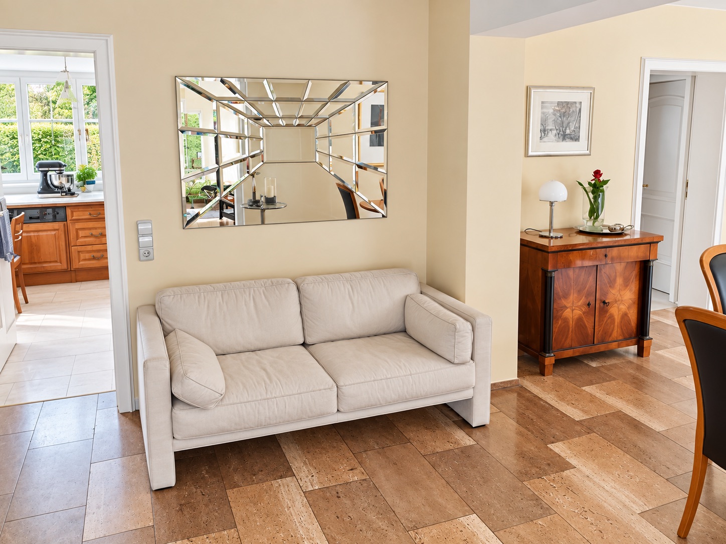Helles Wohnzimmer mit beiger Couch, großem Spiegel und Blick in die Küche.