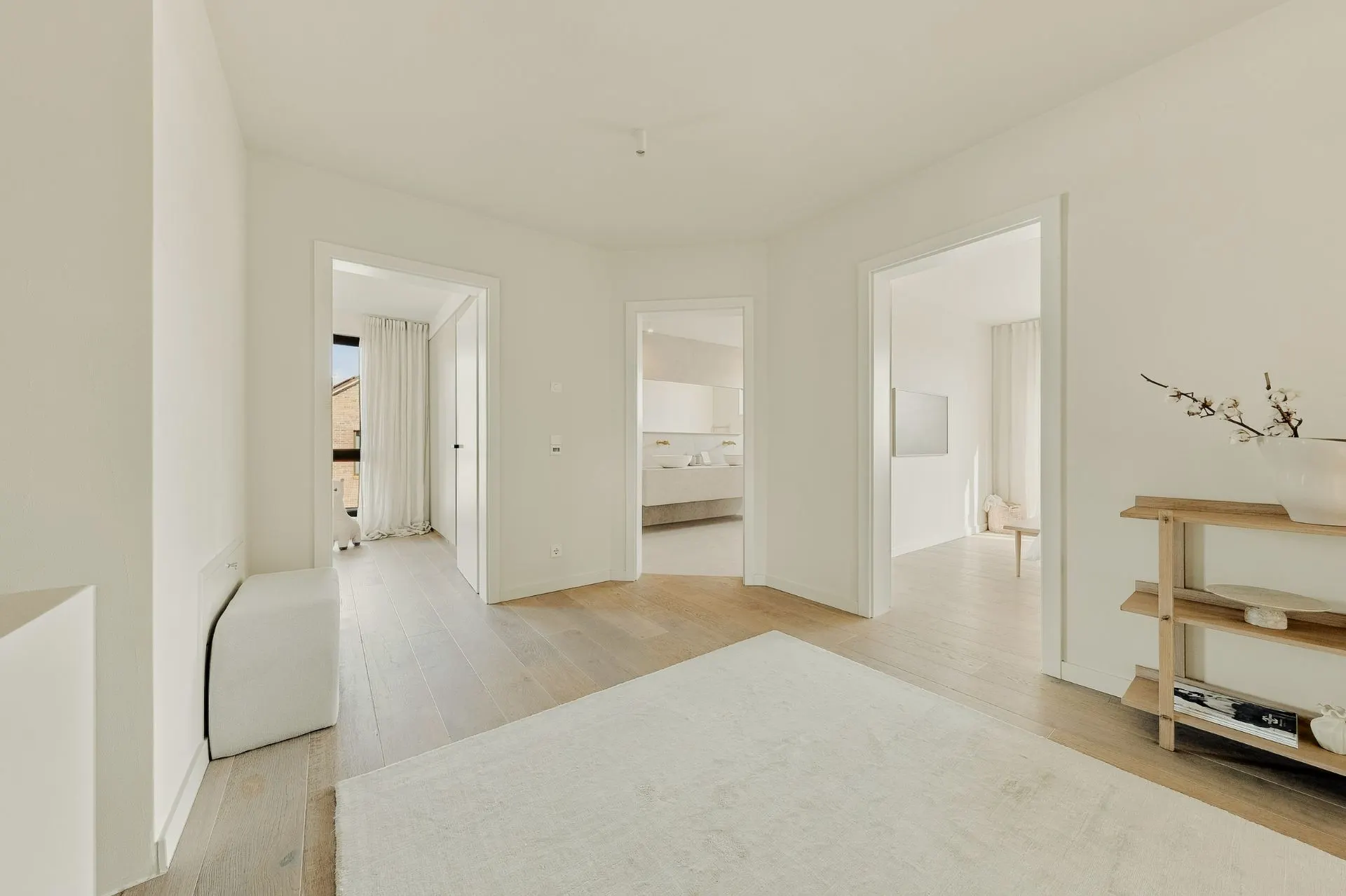 Heller Flur mit Holzboden, drei offenen Türen und Regal mit Vase rechts.