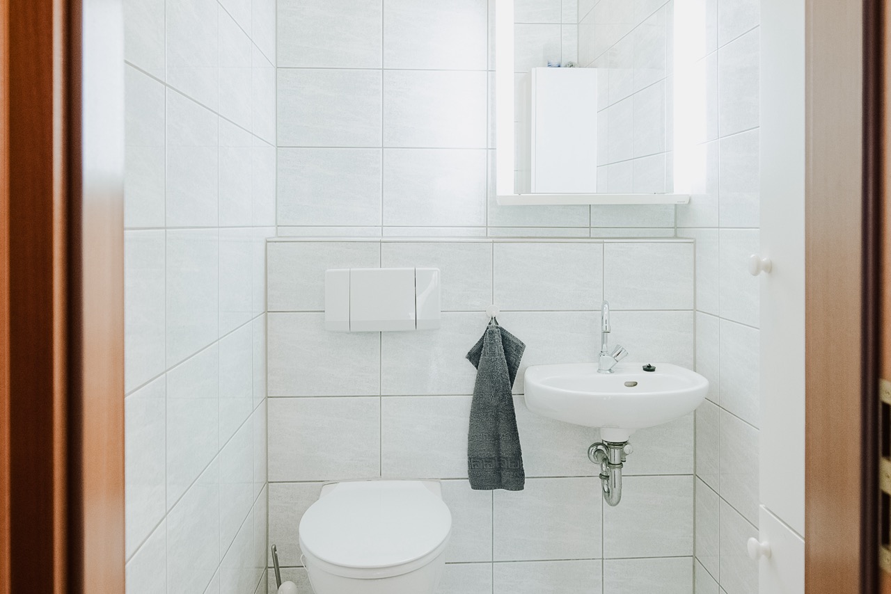 Kleines Badezimmer mit Toilette, Waschbecken, Spiegel und Handtuch an der Wand.