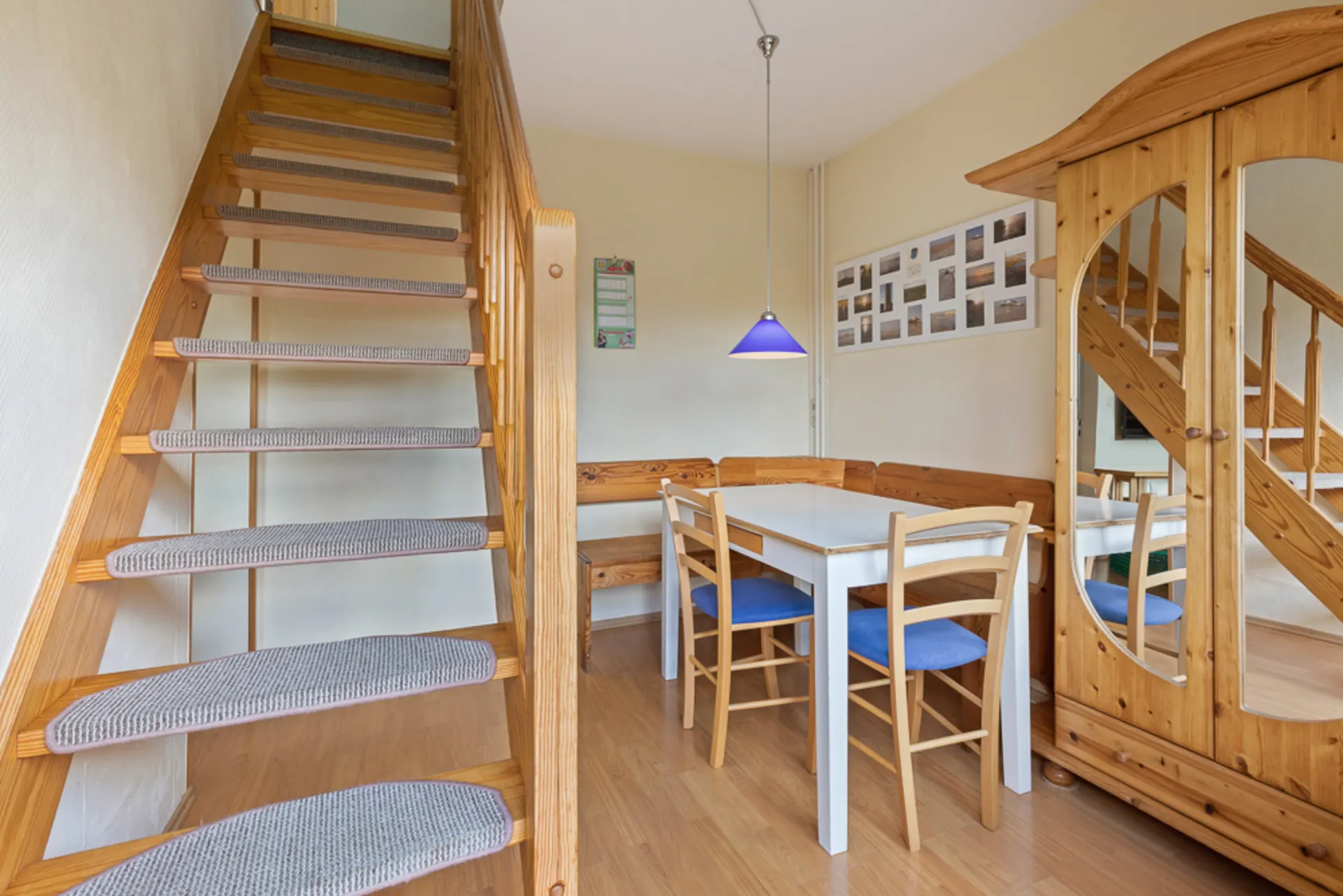 Essbereich mit Holztisch, vier Stühlen, Eckbank, Treppe und Holzschrank mit Spiegel.