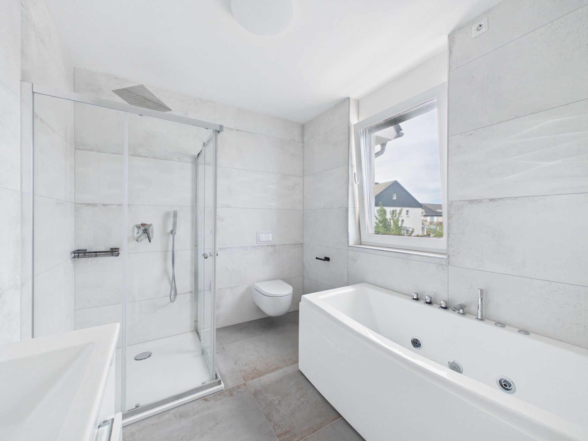 Modernes Bad mit Dusche, Badewanne, WC und Fenster, helle Fliesen.