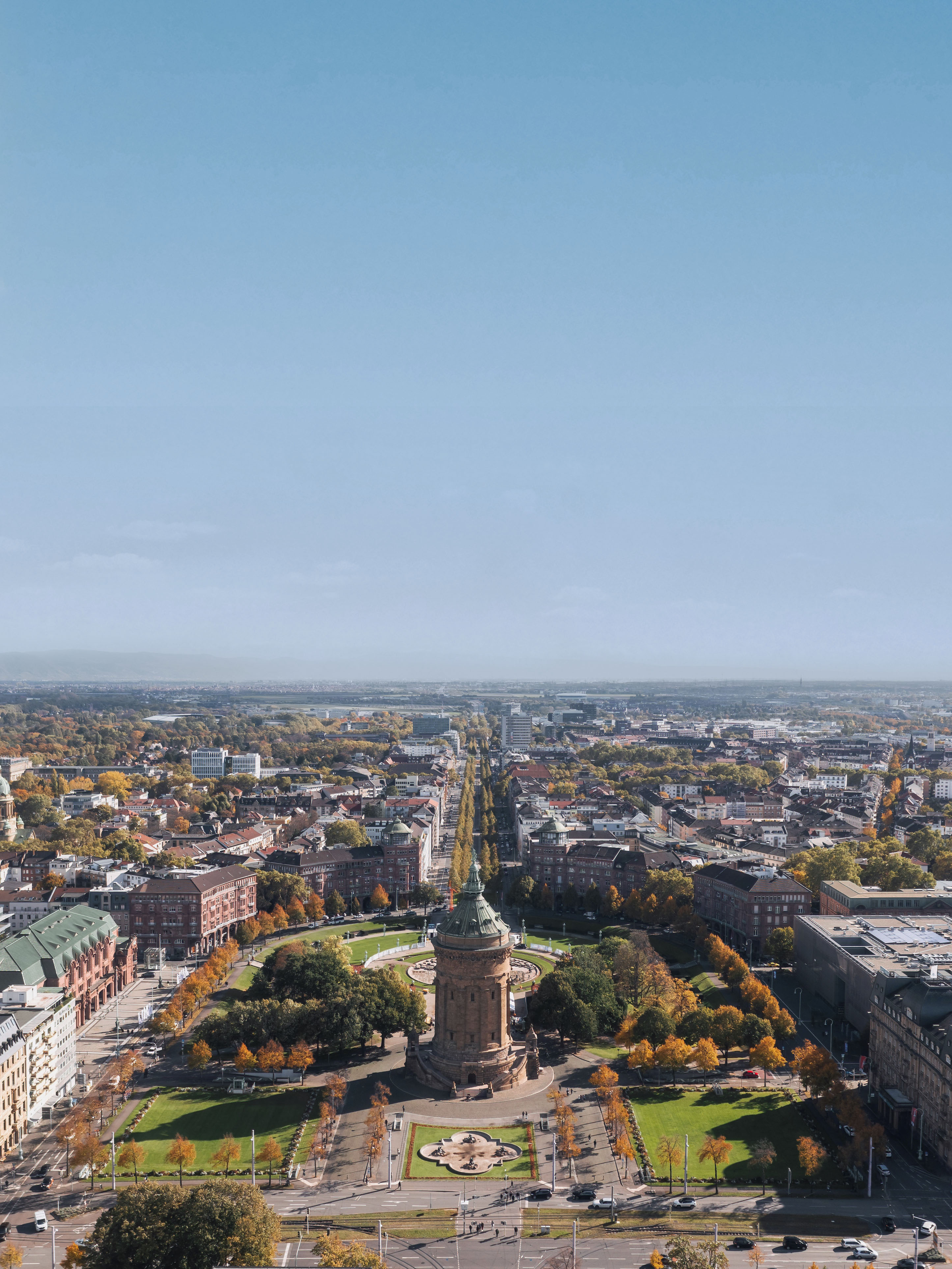 Blick auf eine Stadt mit einem großen runden Turm und umliegendem Park im Vordergrund.