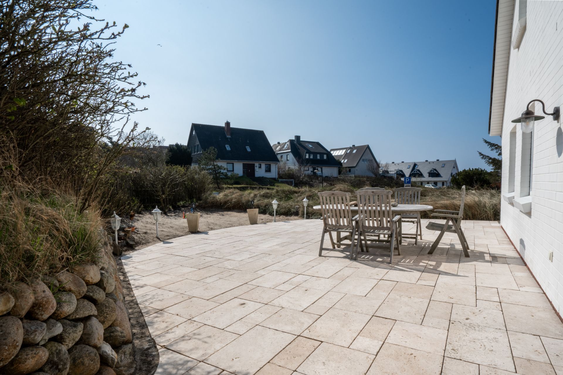 Große Terrasse mit Holztisch und Stühlen, Blick auf Nachbarhäuser und Garten.