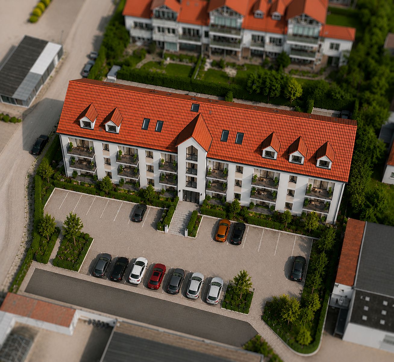 Mehrfamilienhaus mit rotem Dach, Balkonen und Parkplätzen davor, aus der Vogelperspektive.