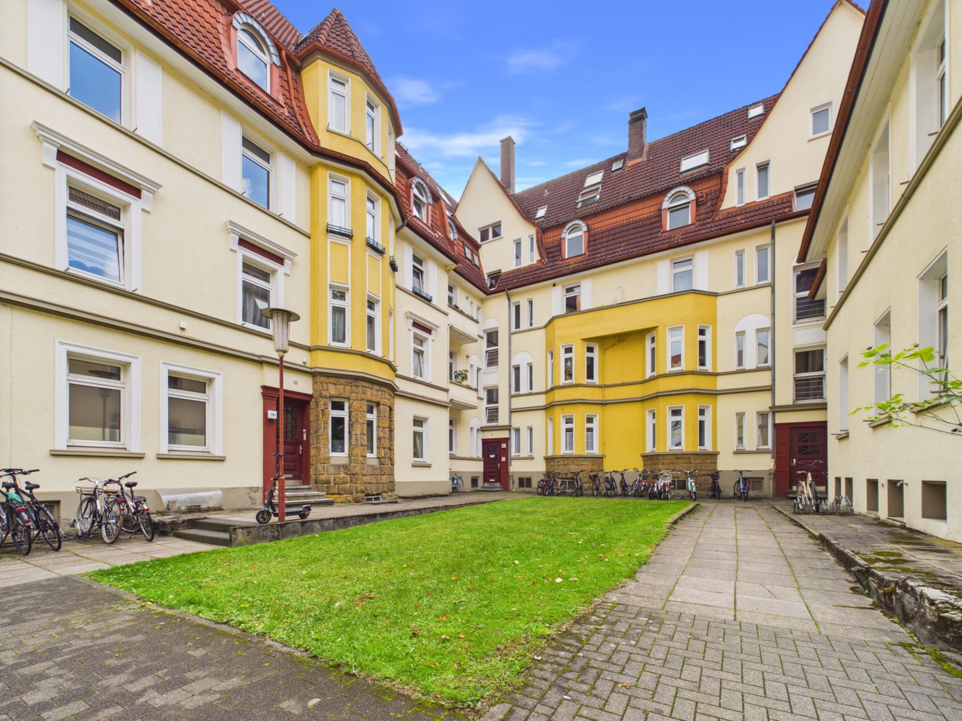 Innenhof eines Wohnhauses mit Fahrrädern, Rasenfläche und gepflasterten Wegen.