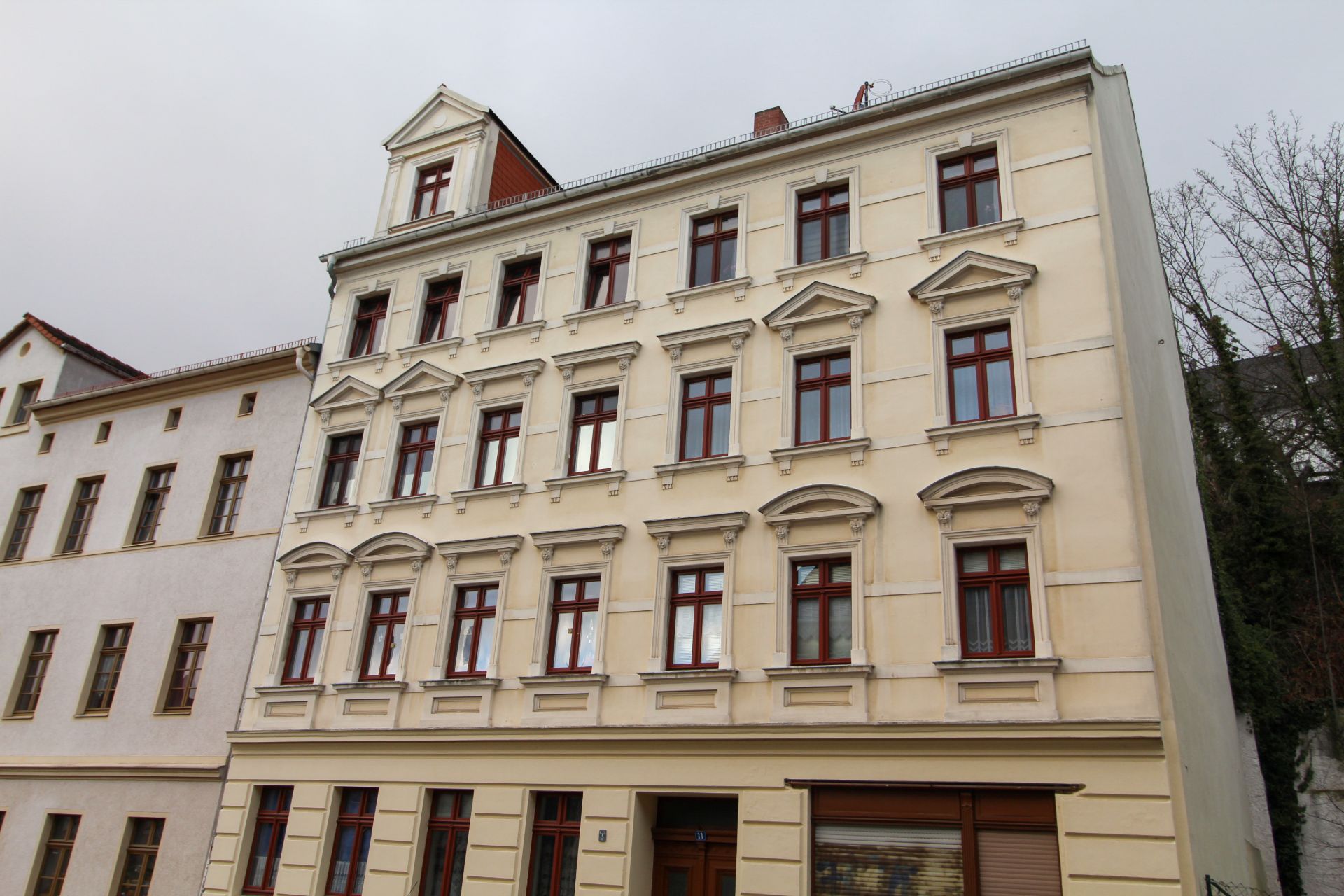 Vierstöckiges Wohngebäude mit vielen Fenstern und hellem Fassadenanstrich.