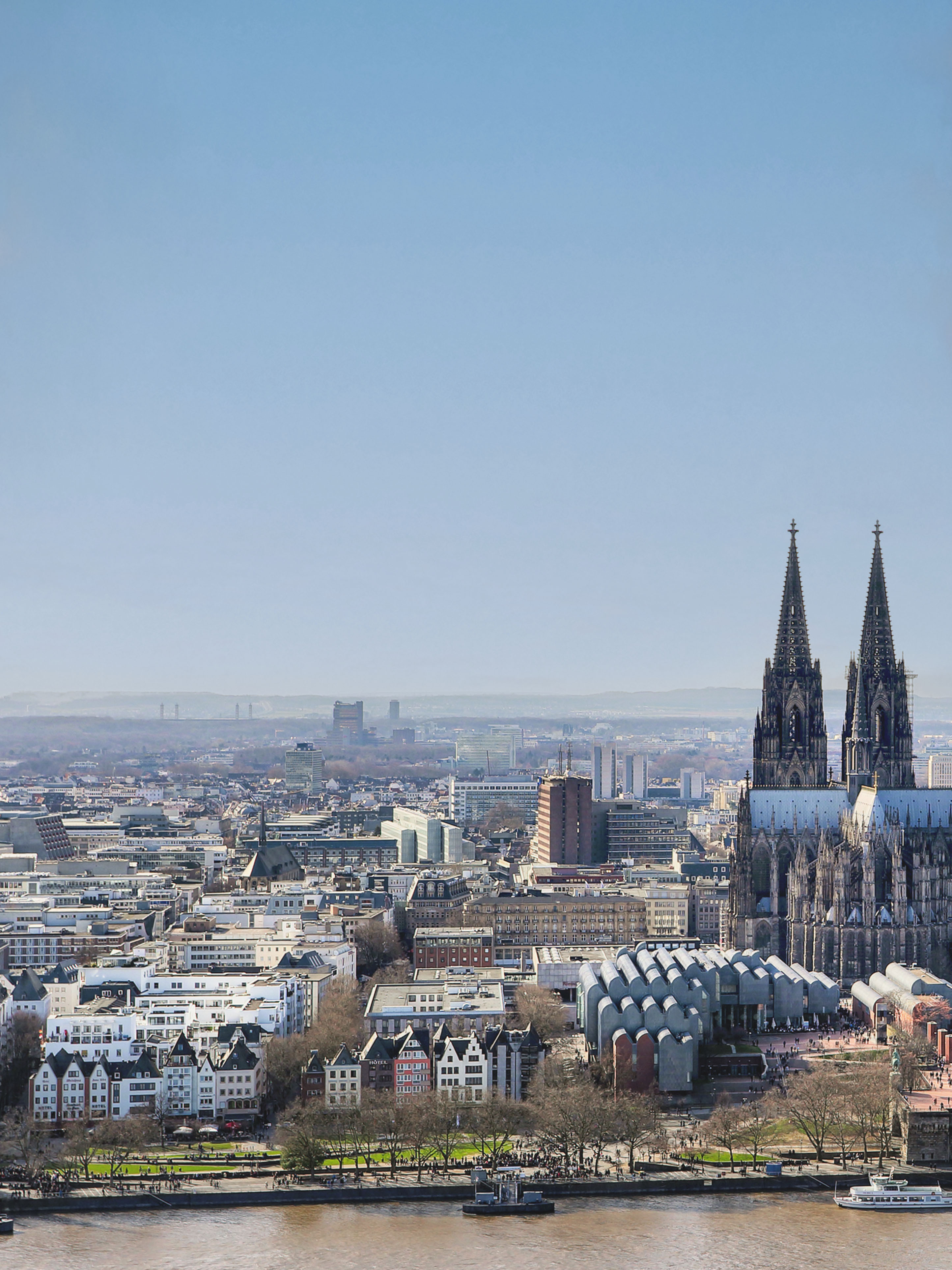 Stadtansicht mit Fluss, historischen Gebäuden und einer großen Kathedrale im Hintergrund.