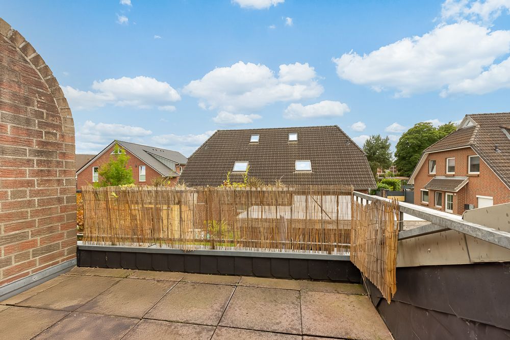Dachterrasse mit Steinboden und Blick auf benachbarte Wohnhäuser.