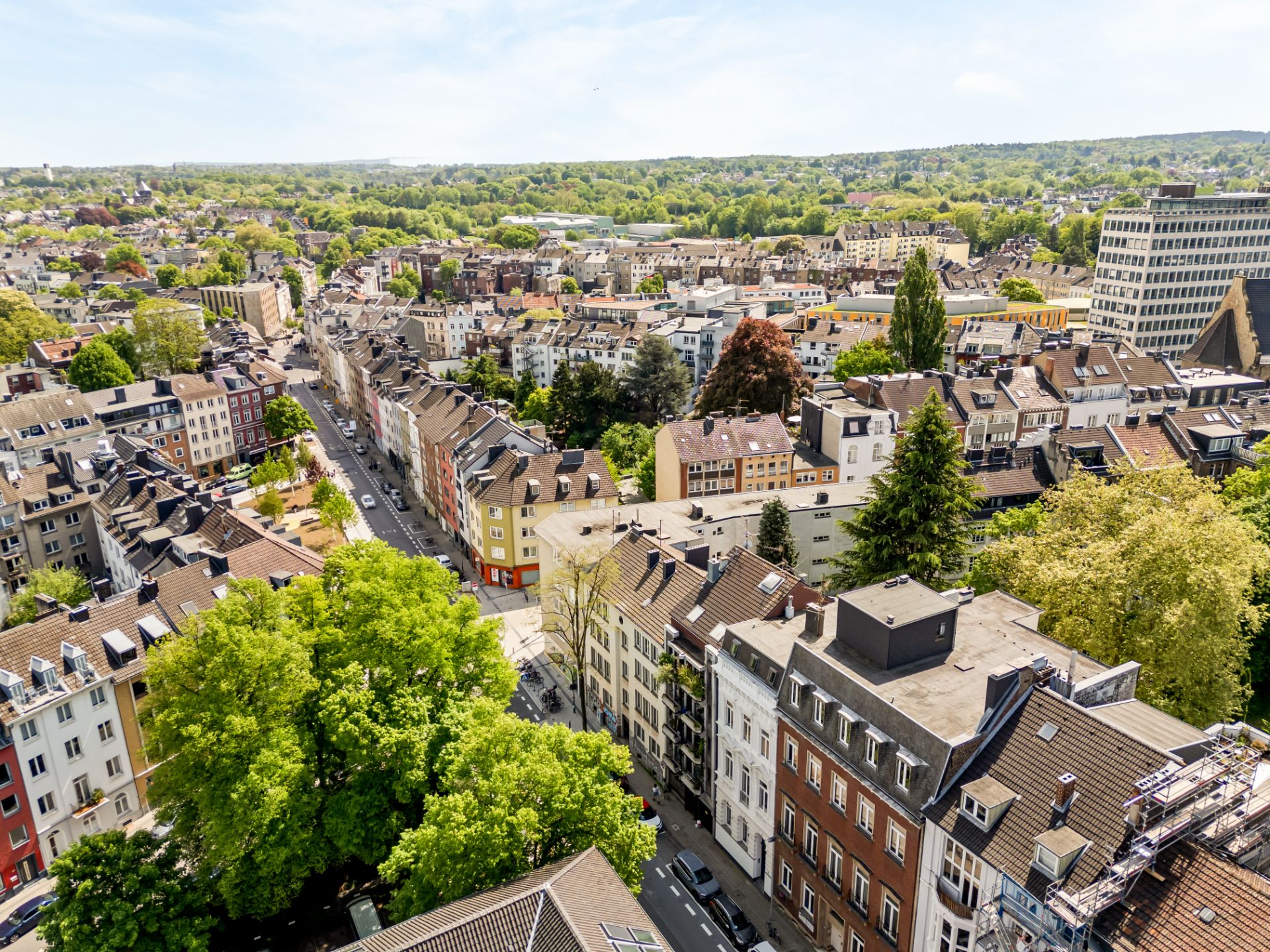 Blick von oben auf ein Wohnviertel mit vielen Häusern, Straßen und grünen Bäumen.
