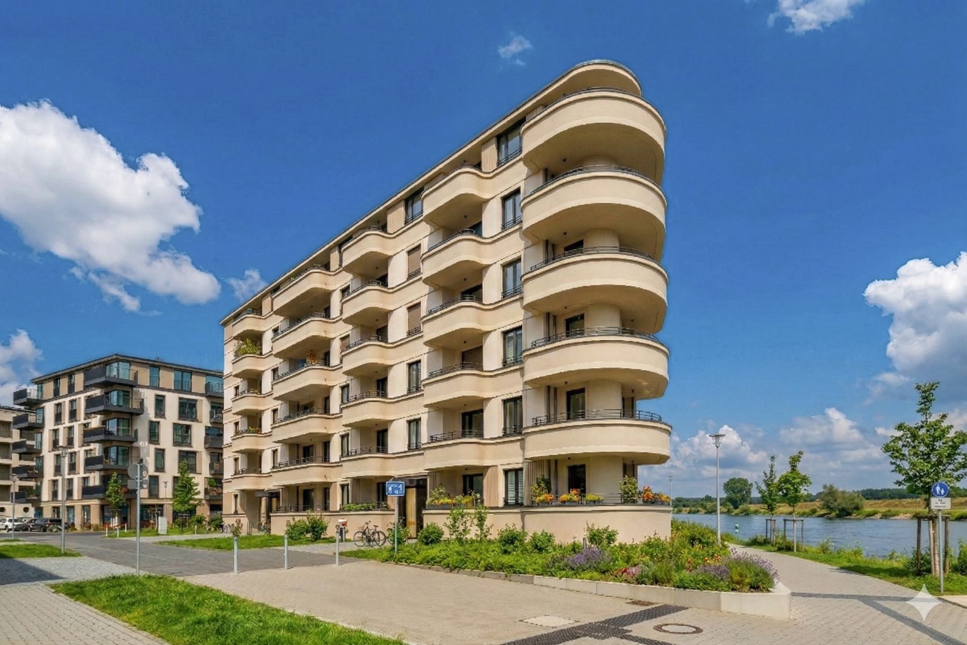Mehrstöckiges Wohngebäude mit mehreren Balkonen und Grünfläche vor dem Haus.