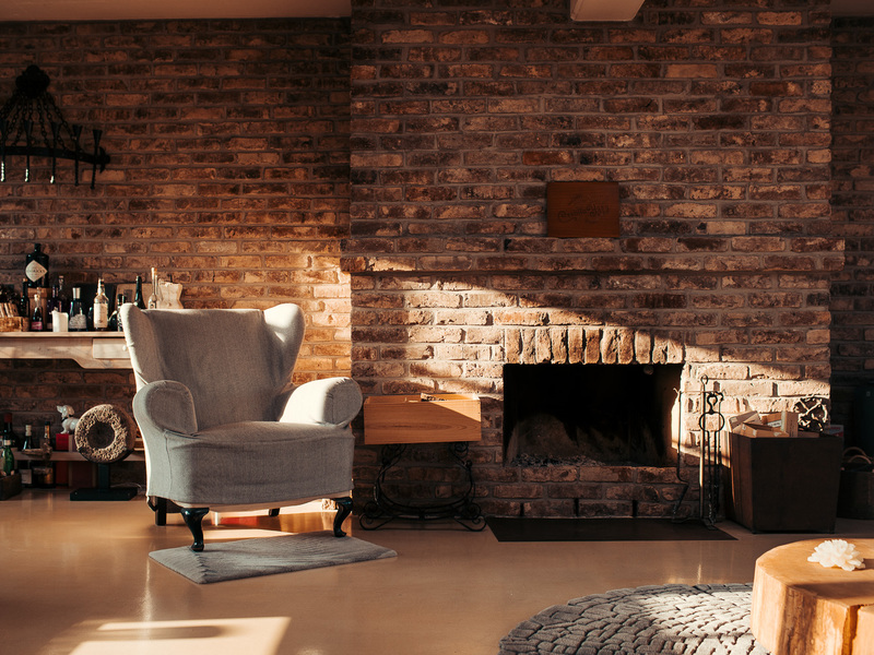 Gemütliches Wohnzimmer mit Sessel vor einer Backsteinwand und Kamin.
