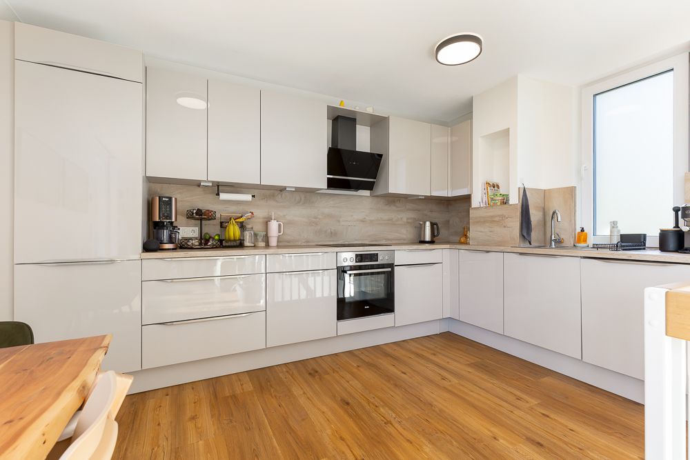 Moderne, helle Einbauküche mit weißen Schränken und Holzfußboden.