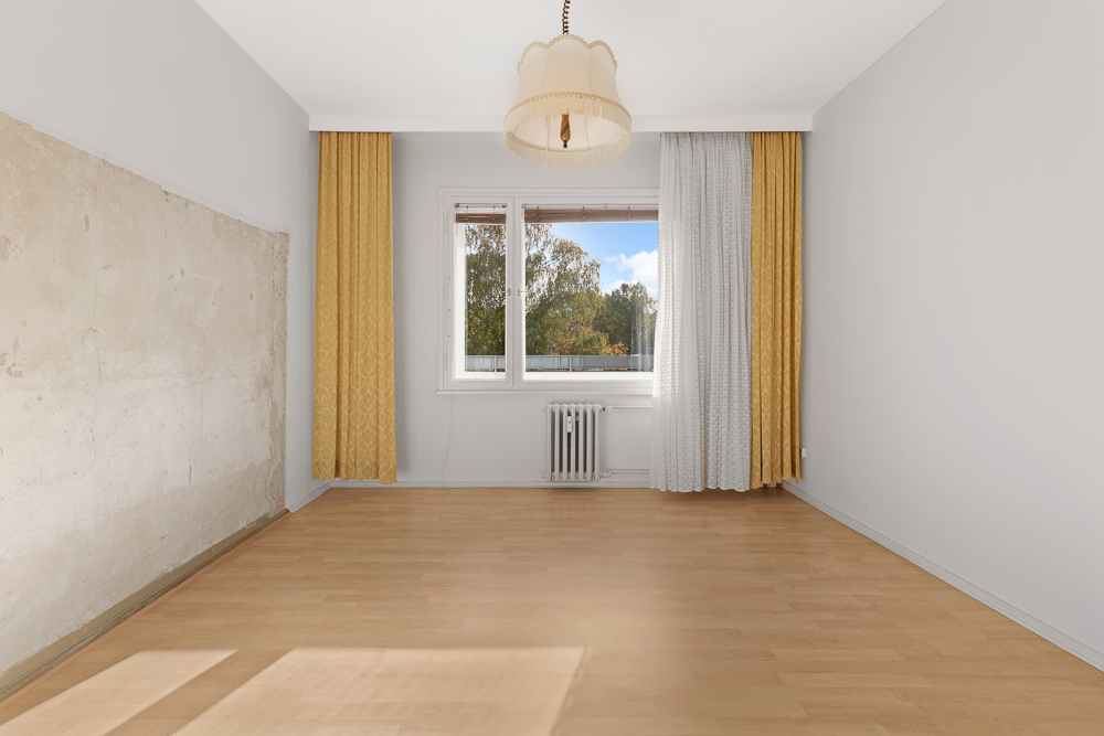 Leeres Zimmer mit Holzfußboden, großem Fenster, gelben Vorhängen und Deckenlampe.