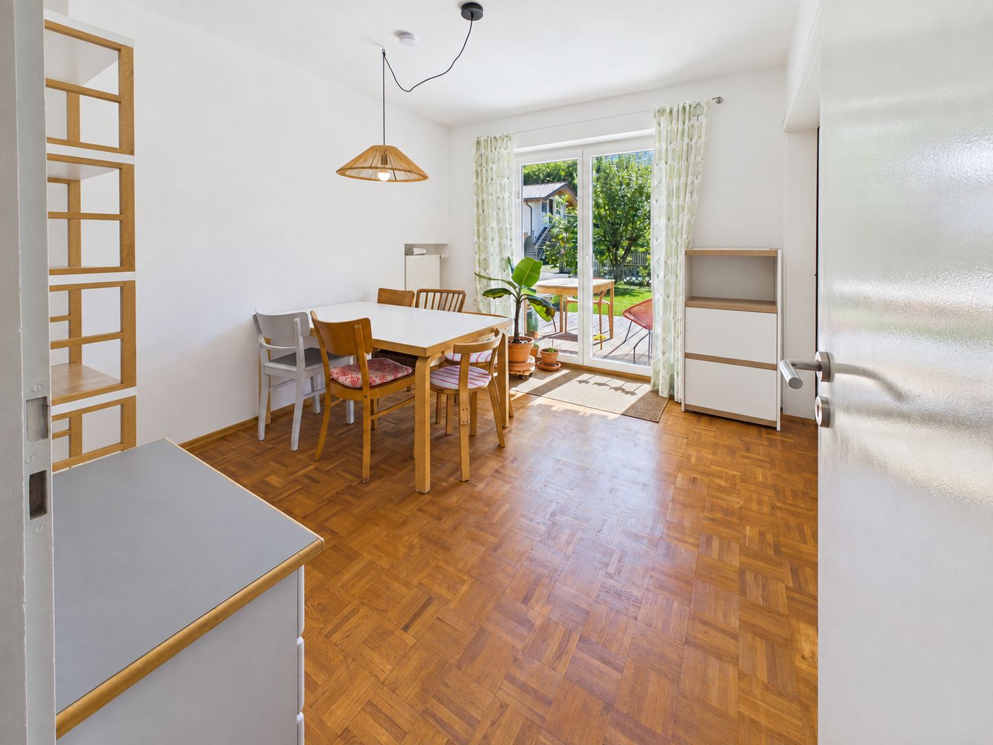 Heller Essbereich mit Holzmöbeln, Parkettboden und Zugang zur Terrasse durch Glastüren.