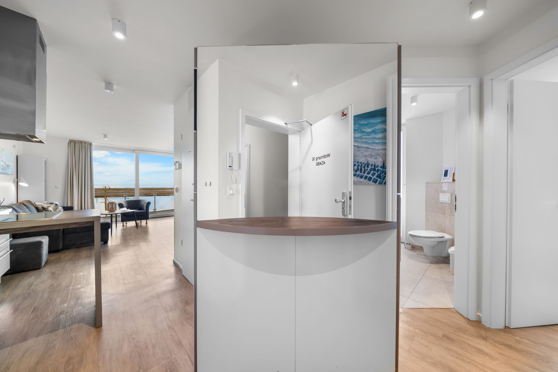 Heller Flur mit offenem Wohnbereich, großem Fenster und Zugang zu einem Badezimmer.