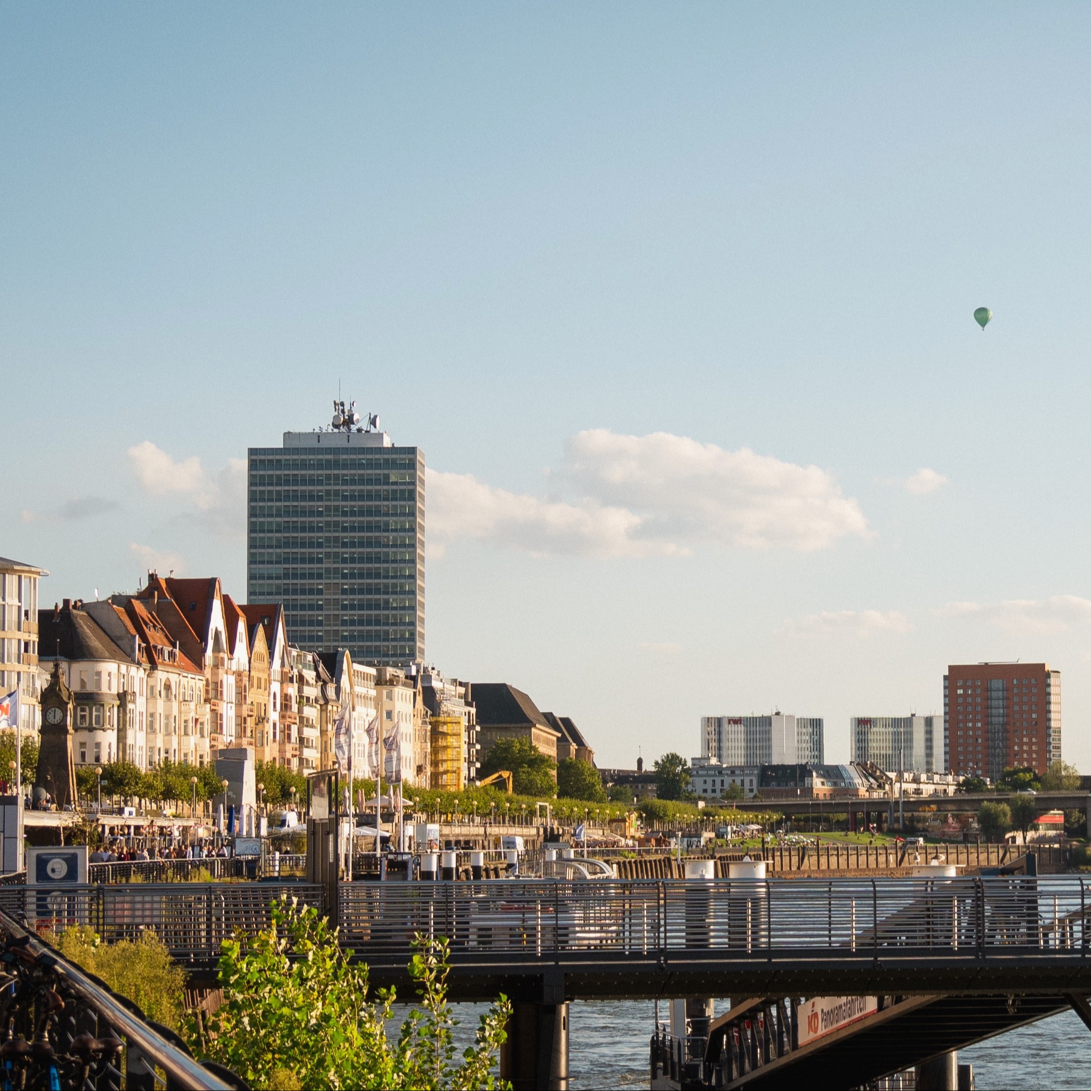 Blick auf Wohnhäuser und moderne Gebäude am Flussufer bei Sonnenschein.