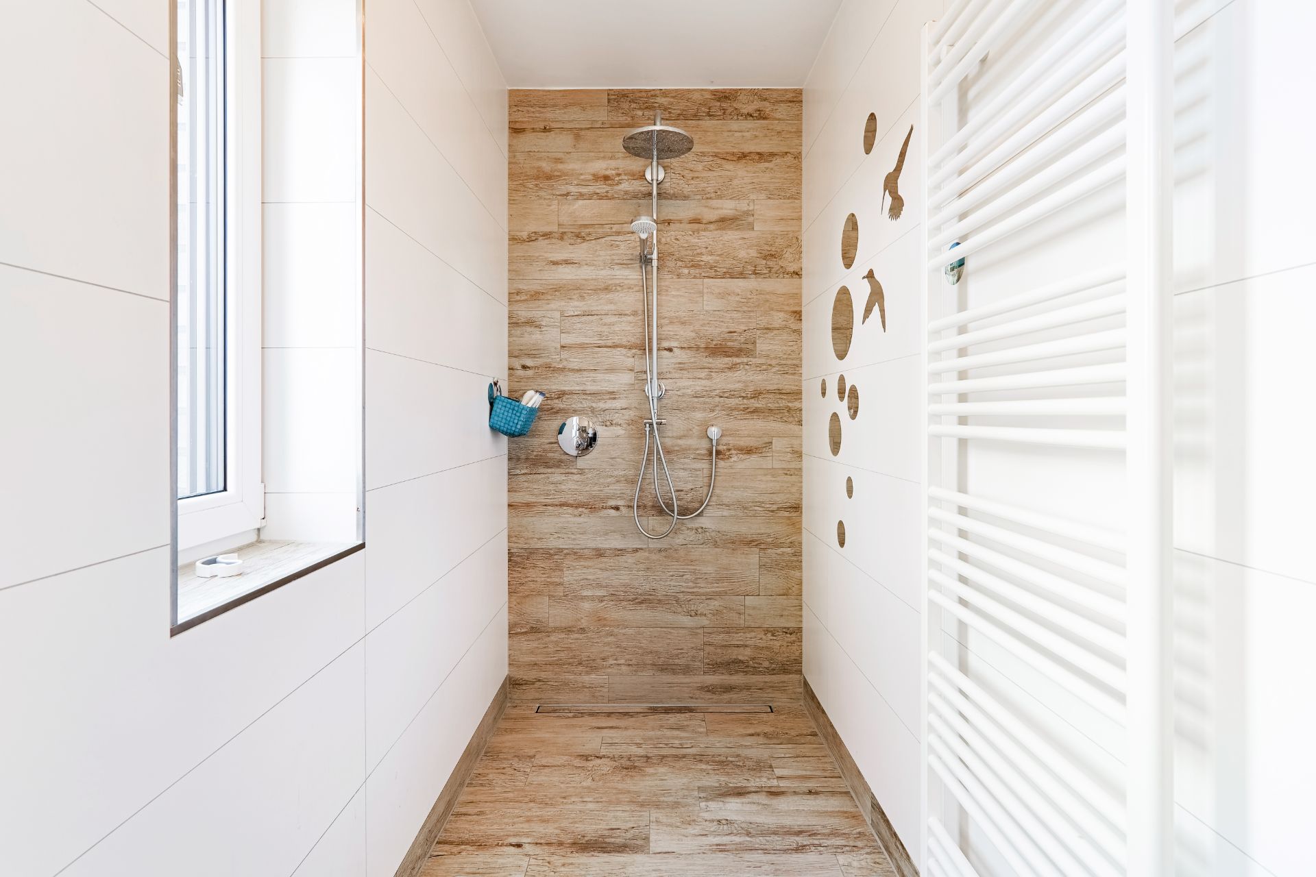 Moderne, begehbare Dusche mit Holzfliesen, Fenster und weißem Handtuchheizkörper.