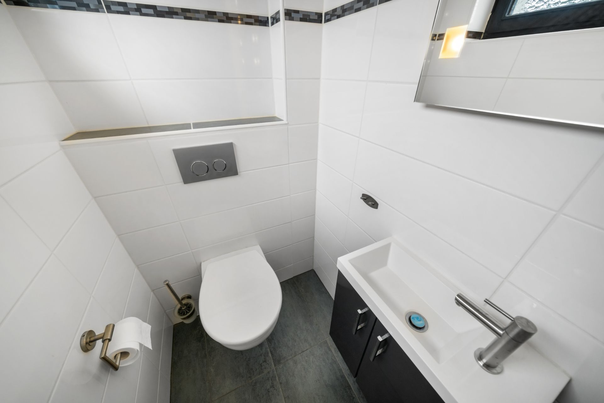 Modernes, kleines Badezimmer mit Wand-WC, Waschbecken, Spiegel und Fliesenboden.