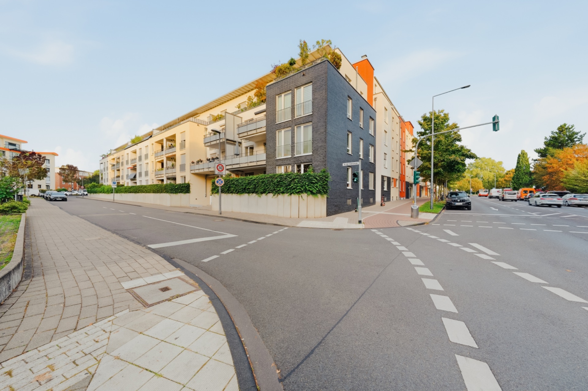 Moderne Wohngebäude an einer Straßenecke mit Balkonen und Gehwegen.