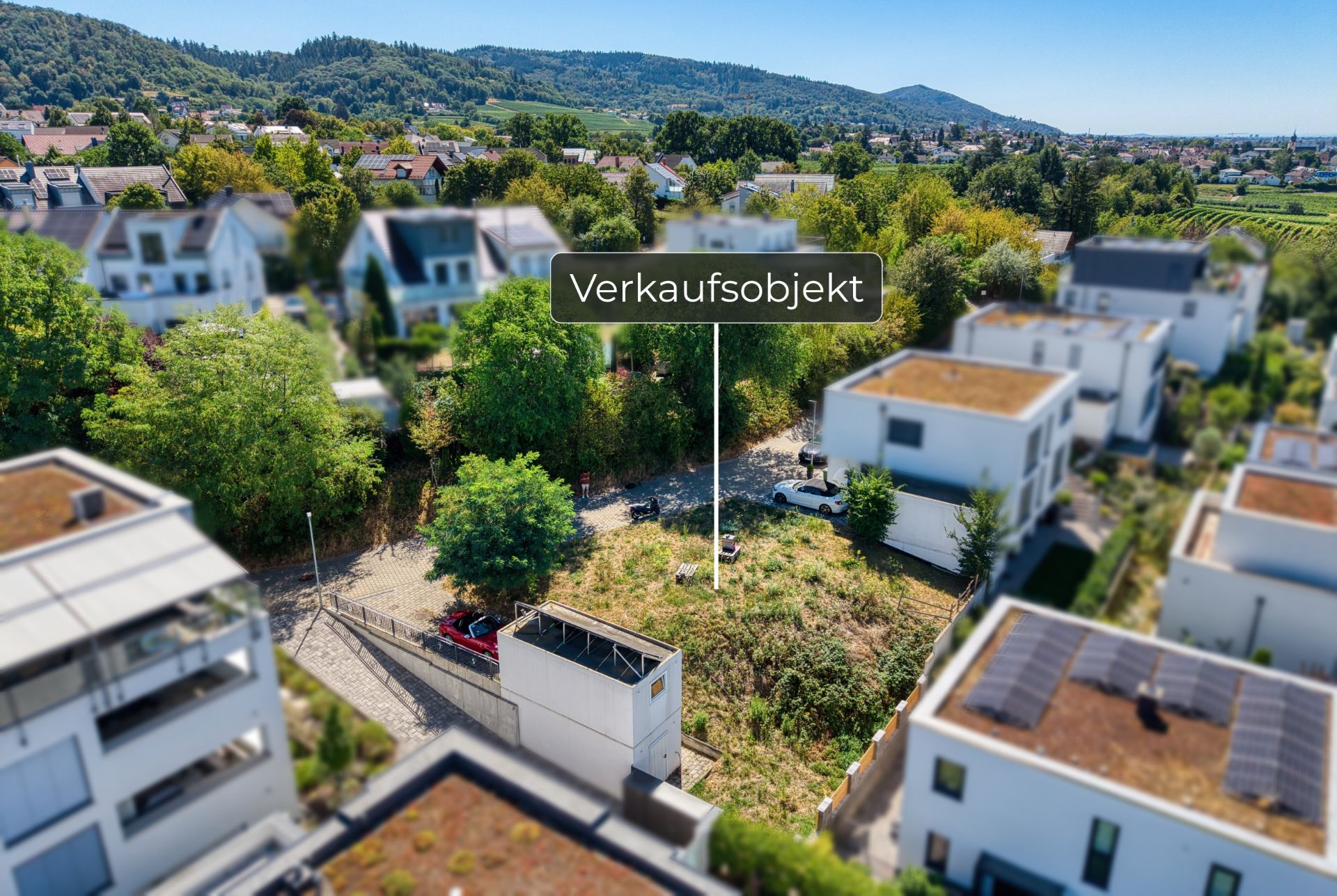 Luftaufnahme eines freien Grundstücks zwischen modernen Wohnhäusern, beschriftet mit 'Verkaufsobjekt'.