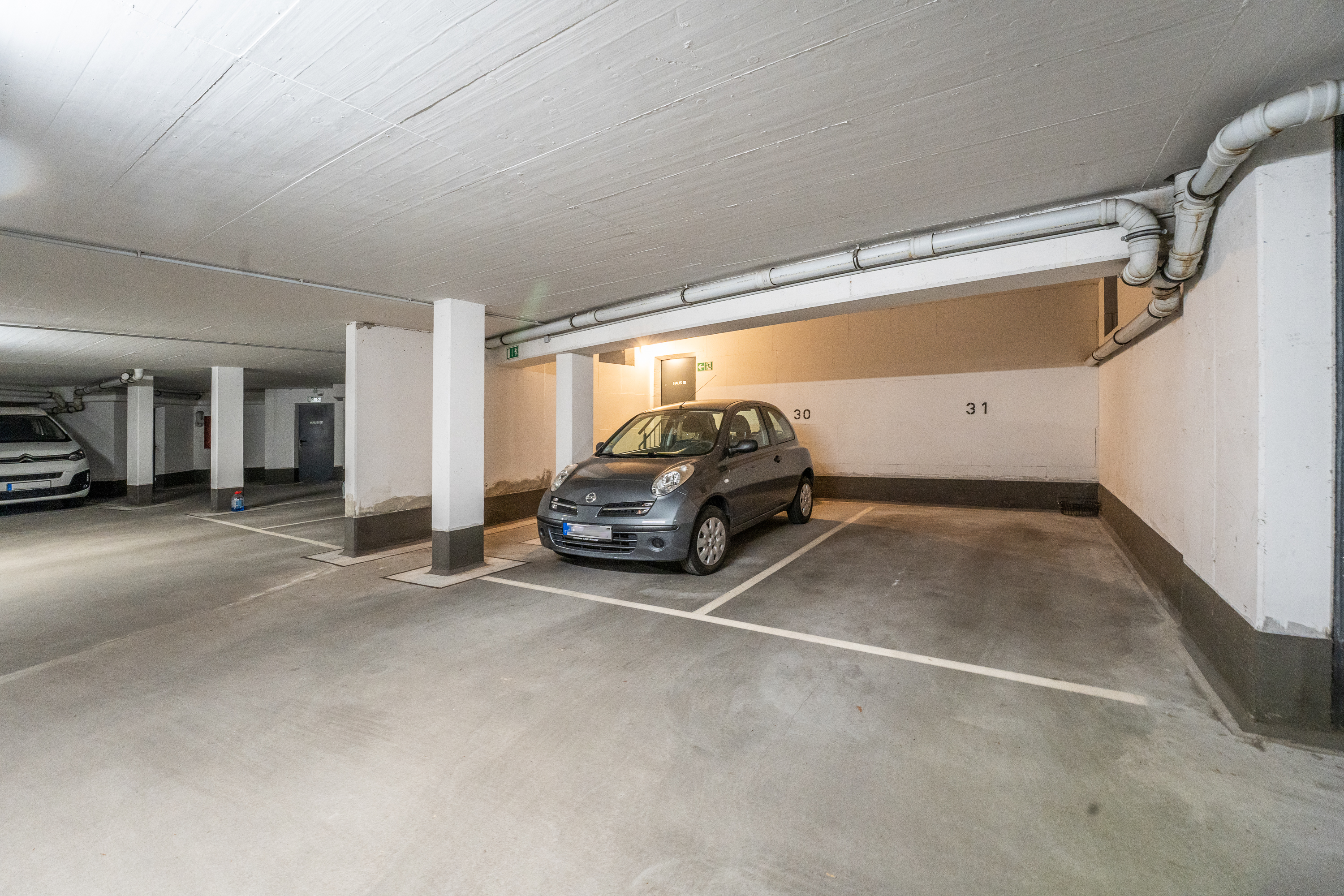 Tiefgaragenstellplatz mit Wänden, Säulen und einem geparkten Auto auf Stellplatz 30.