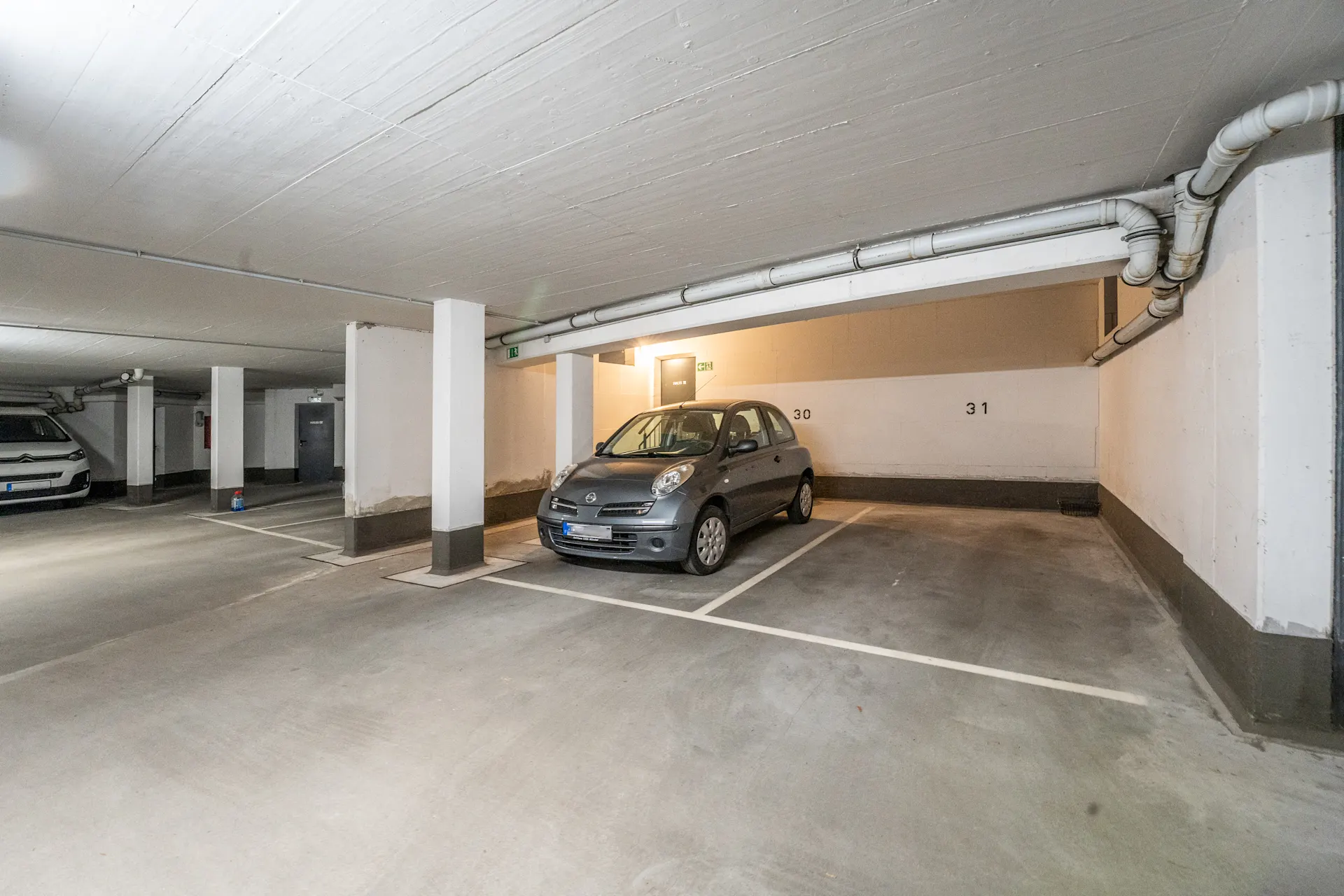 Tiefgaragenstellplatz mit Wänden, Säulen und einem geparkten Auto auf Stellplatz 30.