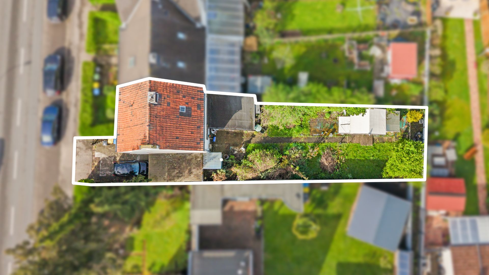 Luftaufnahme eines langen Grundstücks mit Haus, Garten und Terrasse, alles durch weißen Rand hervorgehoben.