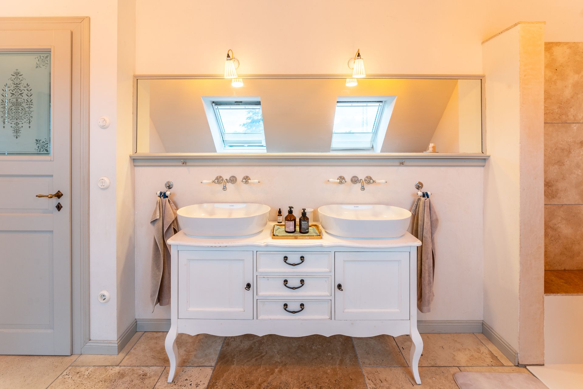 Helles Badezimmer mit zwei Waschbecken auf weißem Waschtisch und großem Spiegel.