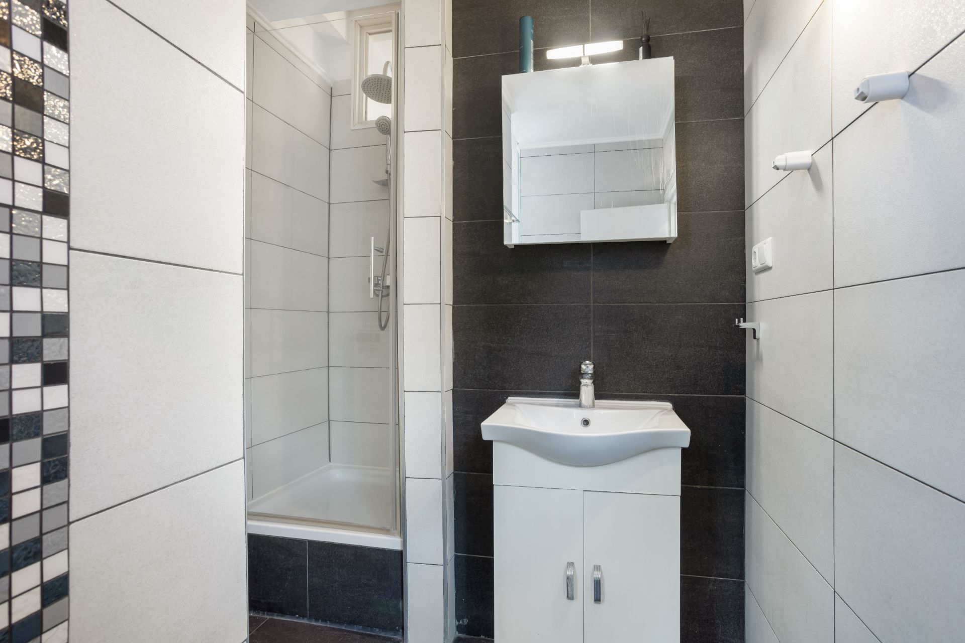 Modernes Badezimmer mit Dusche, Waschbecken und Spiegel an der Wand.