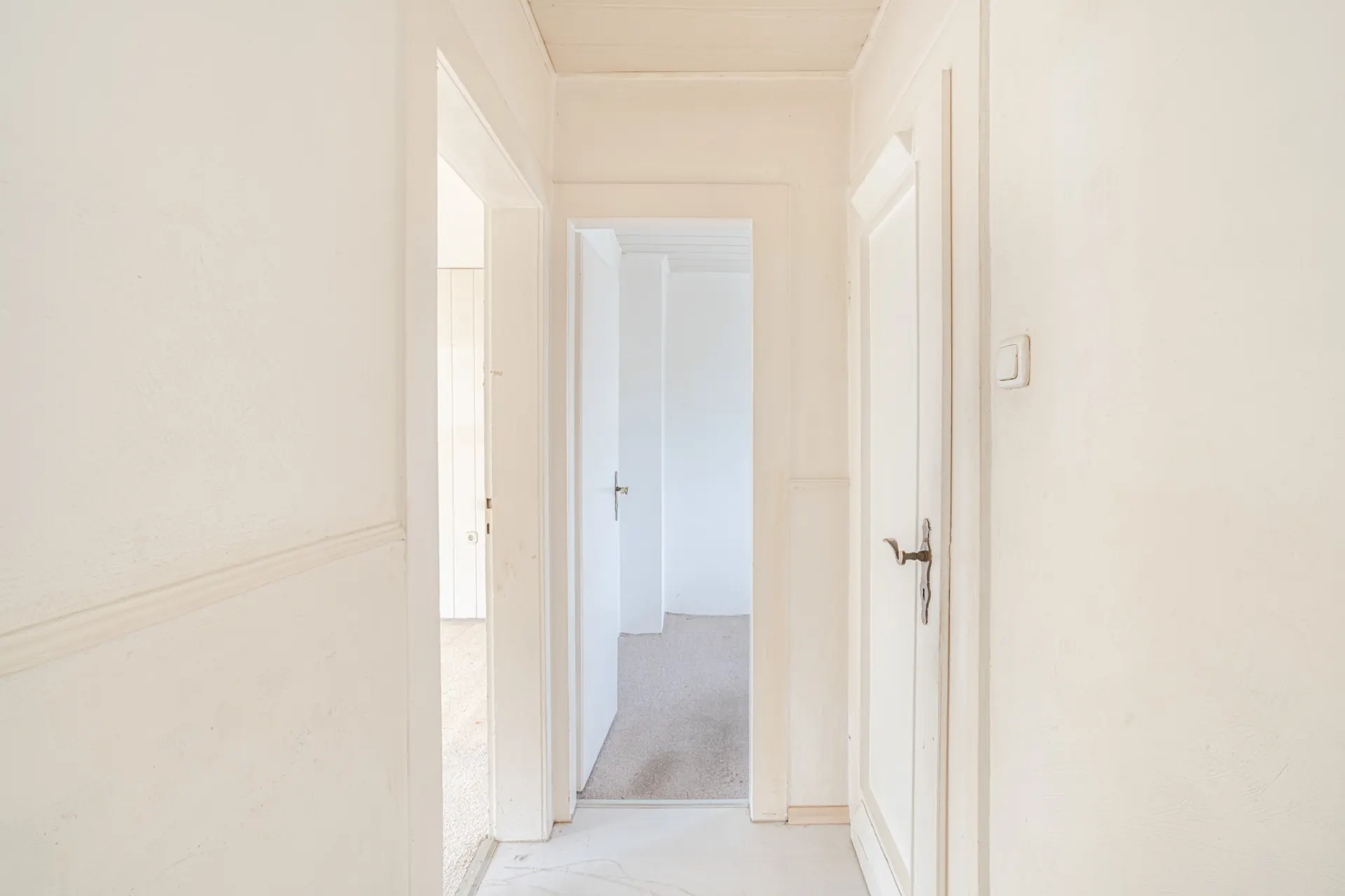 Heller Flur mit mehreren weißen Türen in einem Wohnhaus.