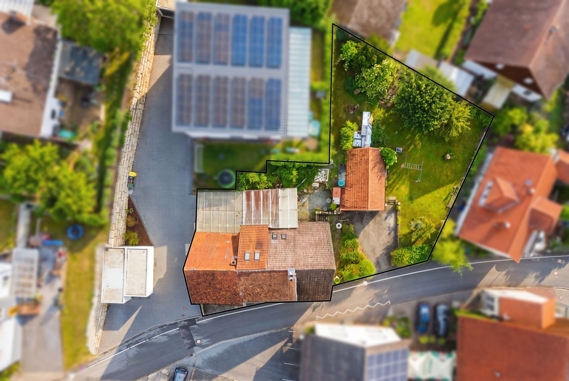 Luftaufnahme eines Wohnhauses mit Garten, das Grundstück ist mit einer schwarzen Linie markiert.