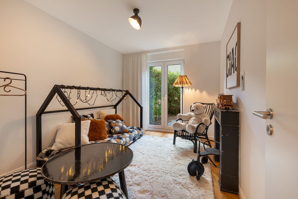 Gemütliches Kinderzimmer mit Kuschel-Tier, Teppich, kleinem Bett und Glastür zum Garten.