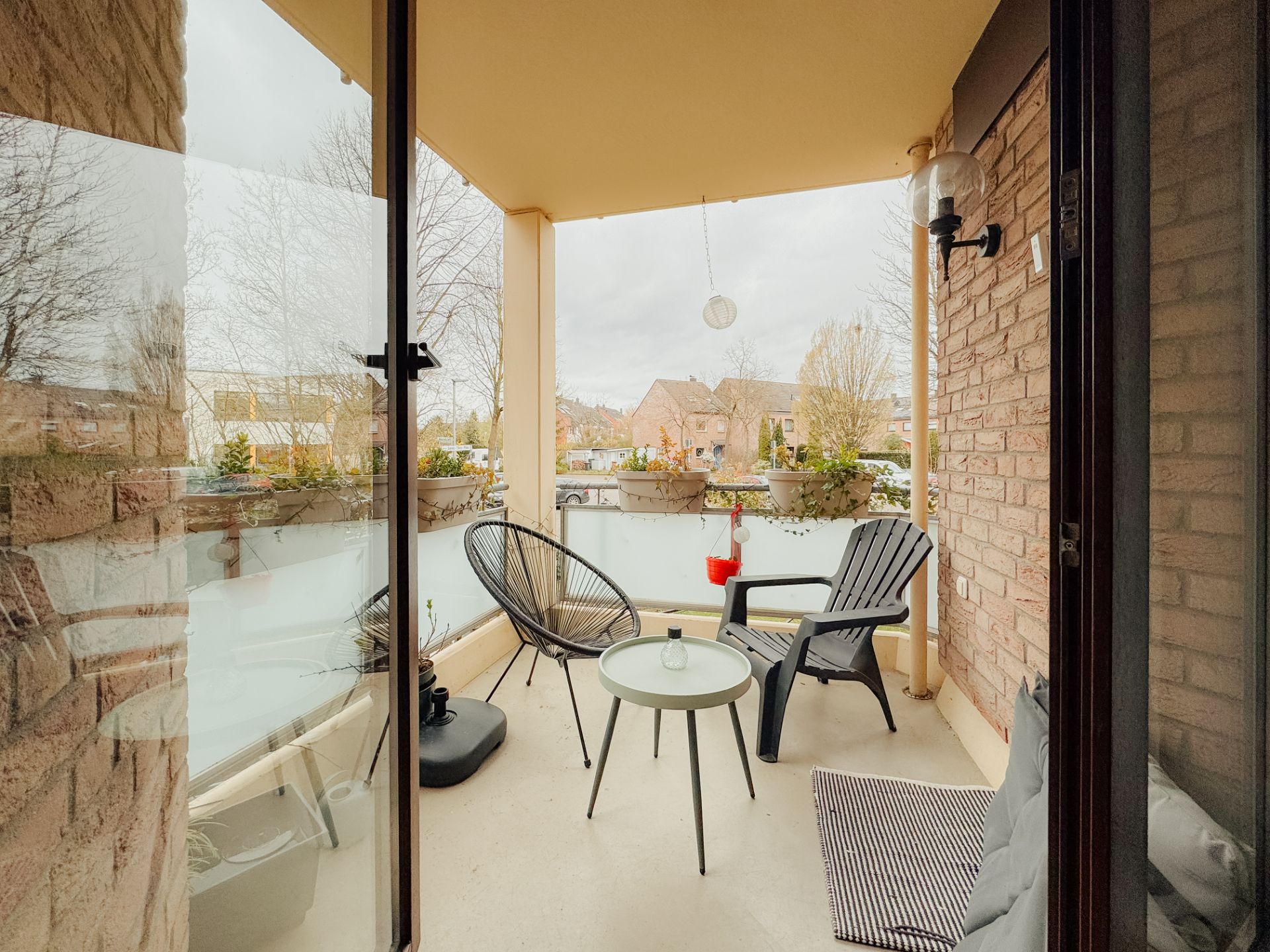 Überdachter Balkon mit zwei Stühlen, einem Tisch und Blumenkästen an der Brüstung.