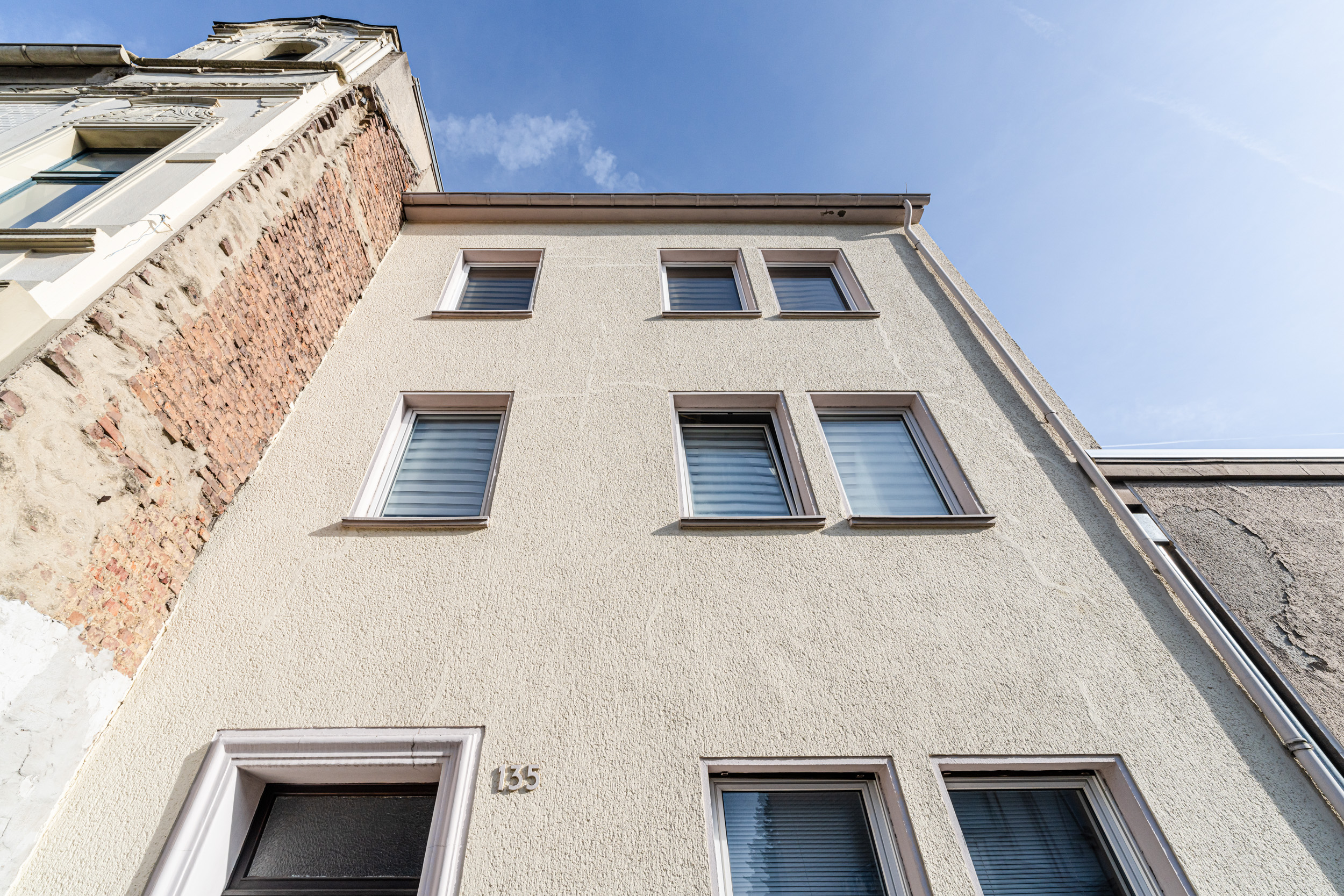 Vorderansicht eines mehrstöckigen Wohnhauses mit mehreren Fenstern und Hausnummer 135.