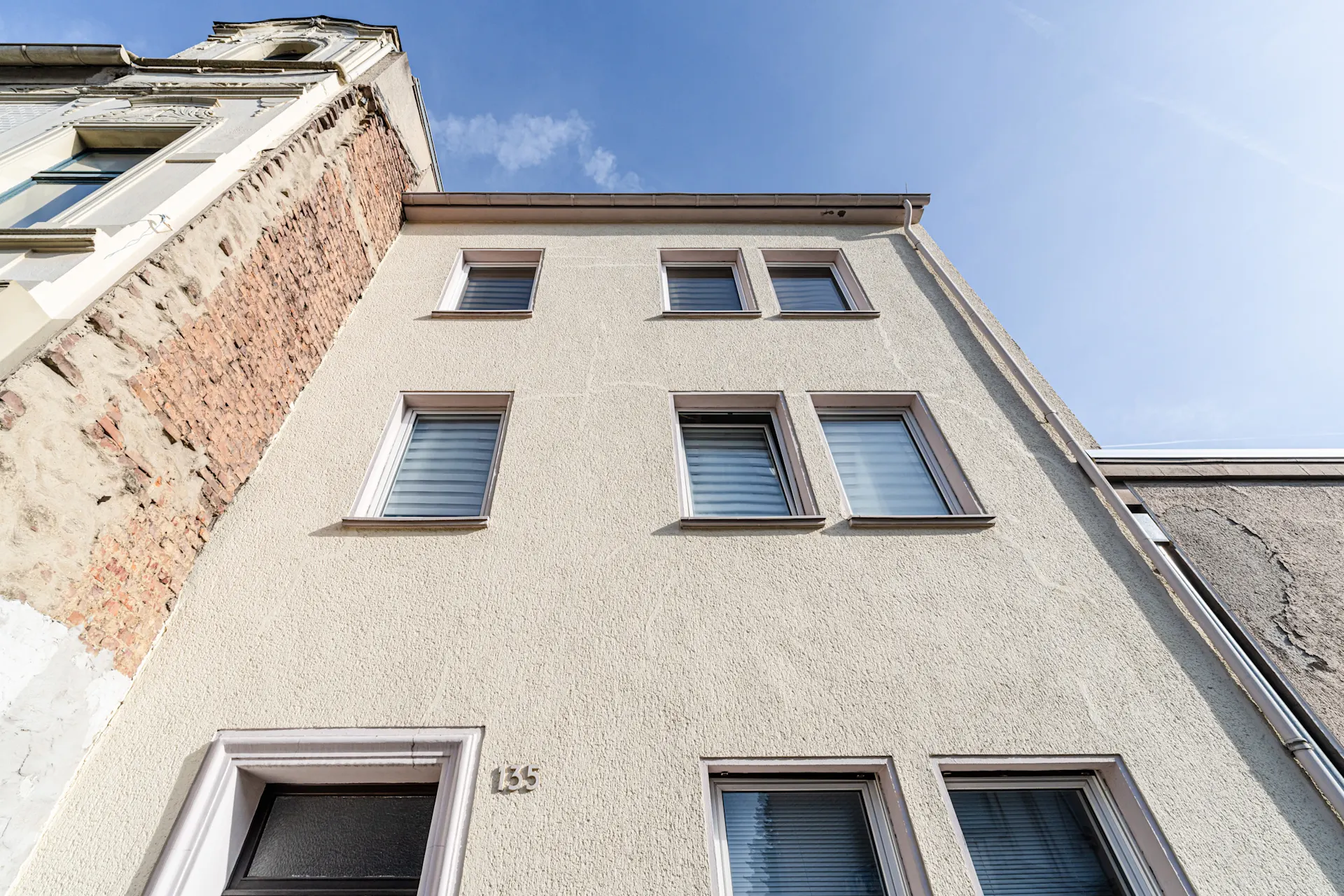 Vorderansicht eines mehrstöckigen Wohnhauses mit mehreren Fenstern und Hausnummer 135.