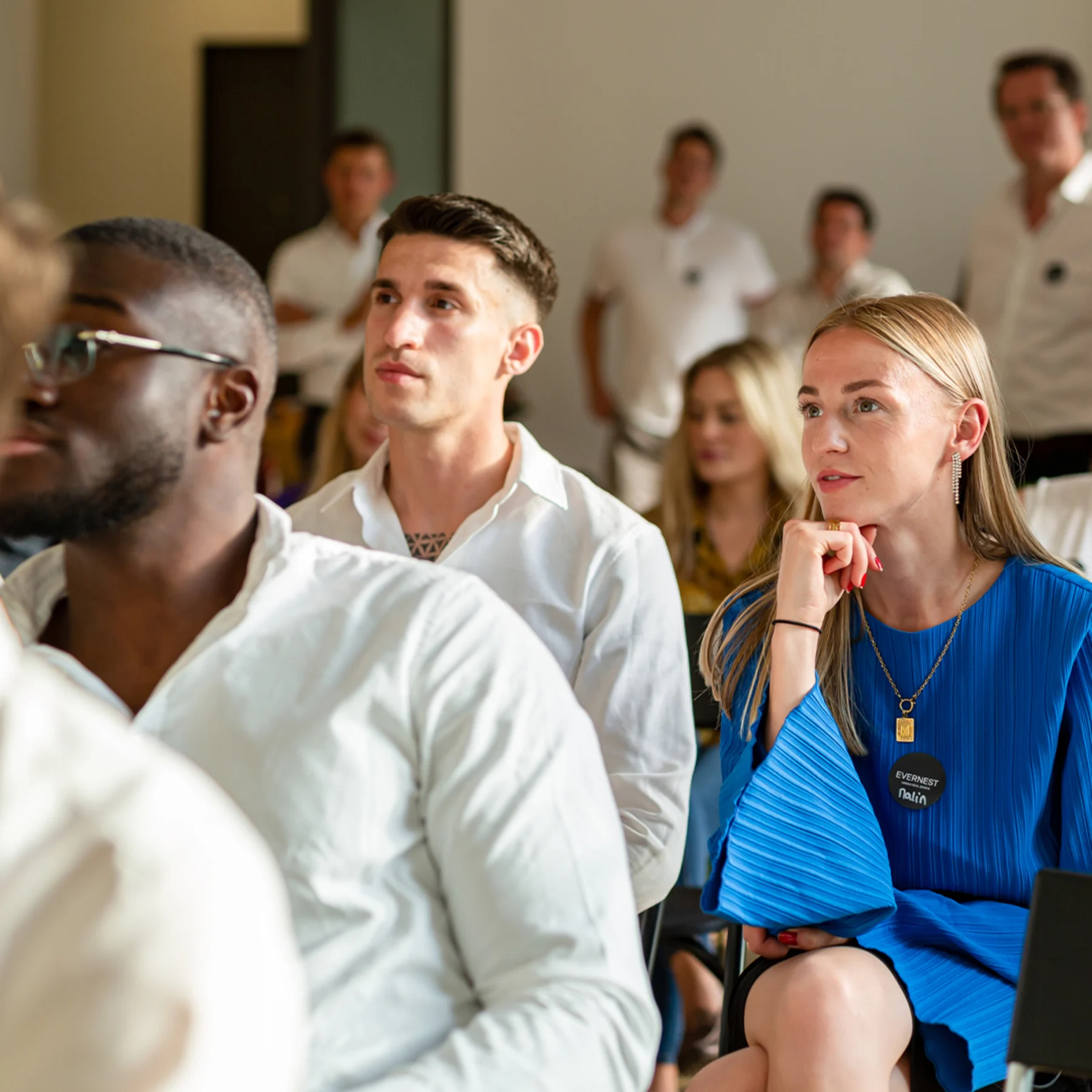 Mehrere Personen sitzen aufmerksam in einem Raum und hören einer Präsentation zu.