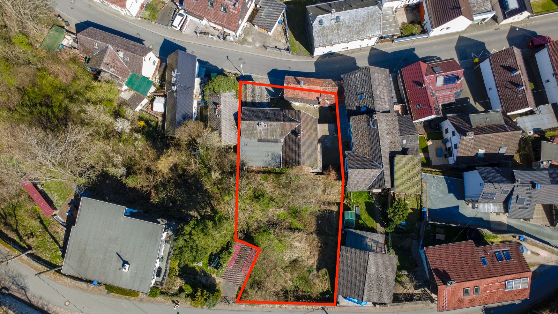 Luftaufnahme eines Wohngrundstücks mit Haus und Garten, rot umrandet.