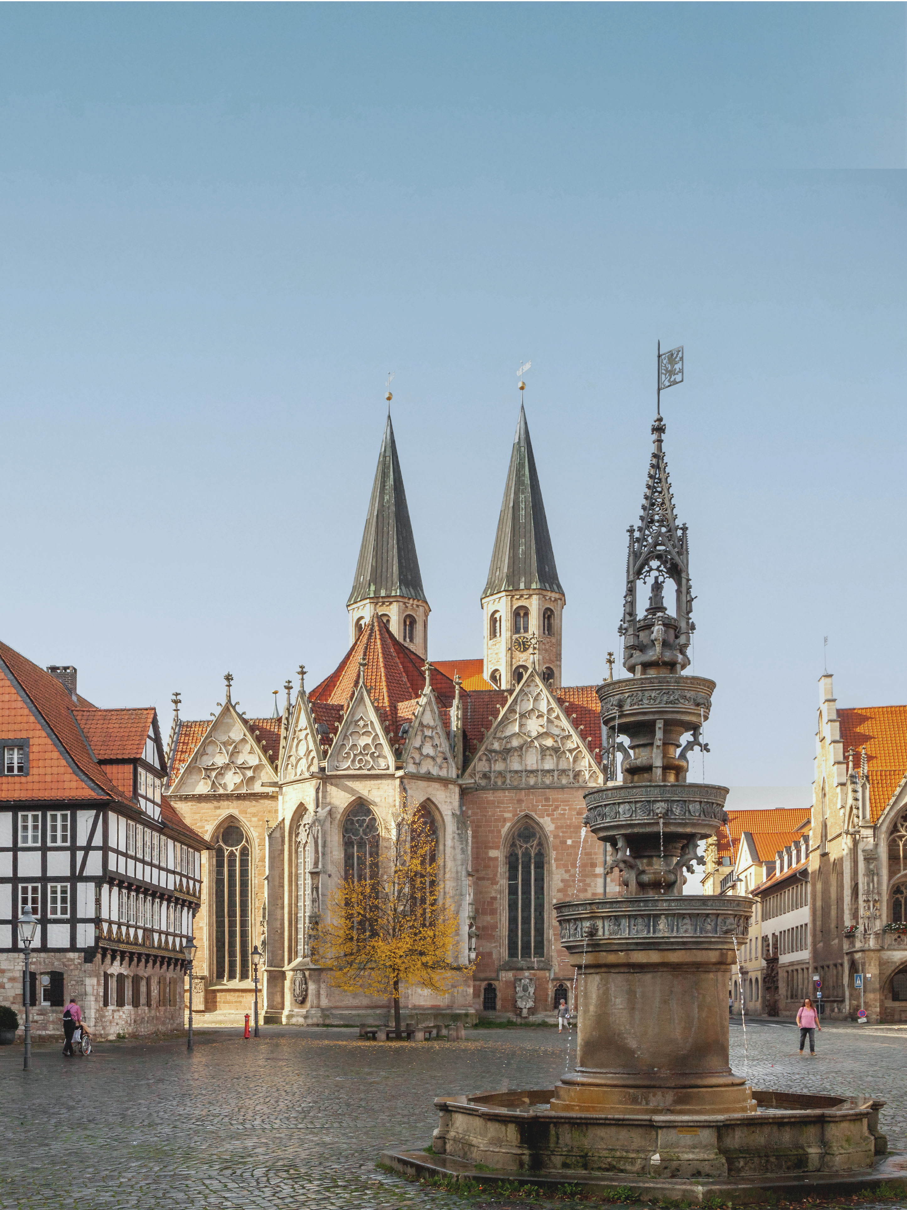 Großer Platz mit Brunnen, Gehsteig, Fachwerkhaus und einer Kirche im Hintergrund.