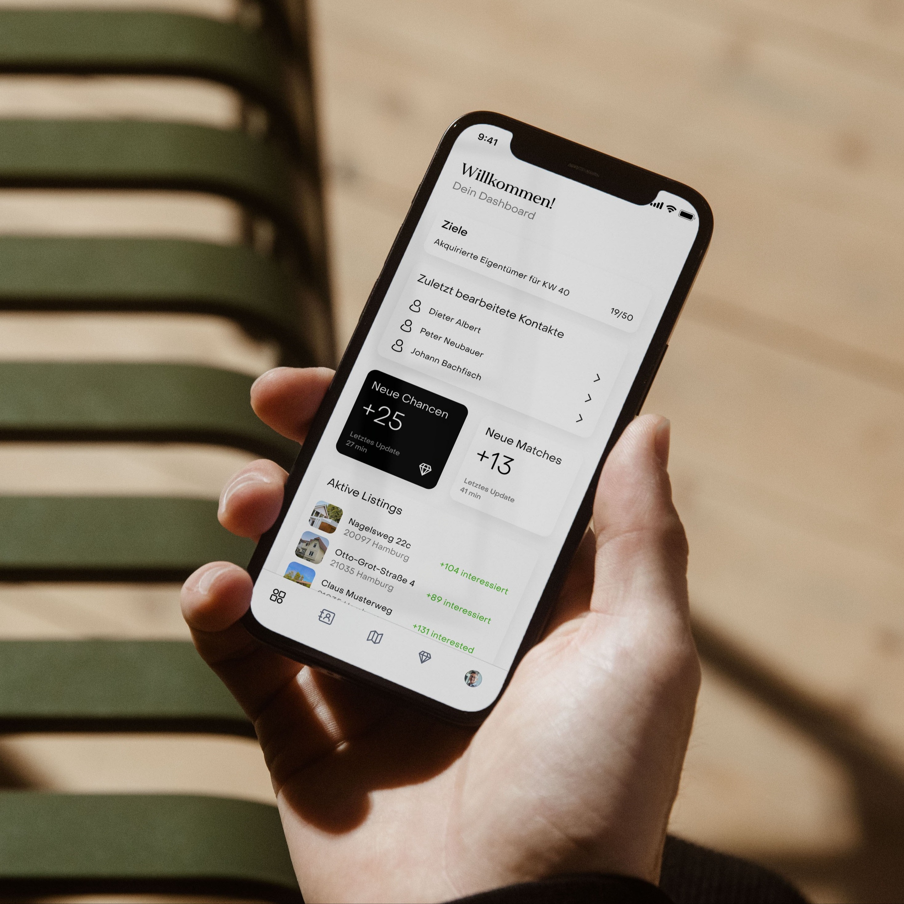 Eine Hand hält ein Smartphone mit einer auf Deutsch angezeigten Dashboard-App.